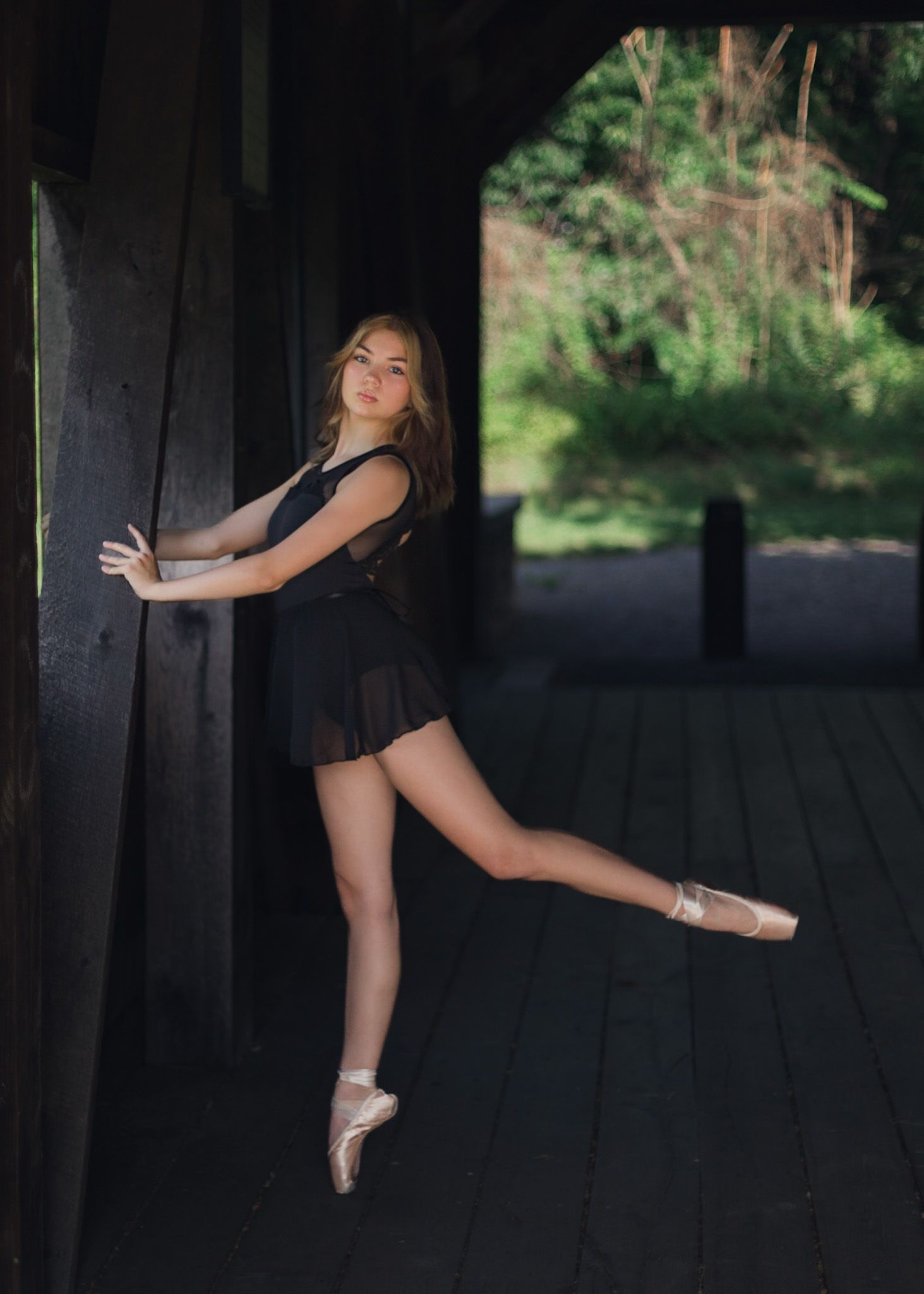 Dancer on pointe leaning against a wooden post in Camp Hill
