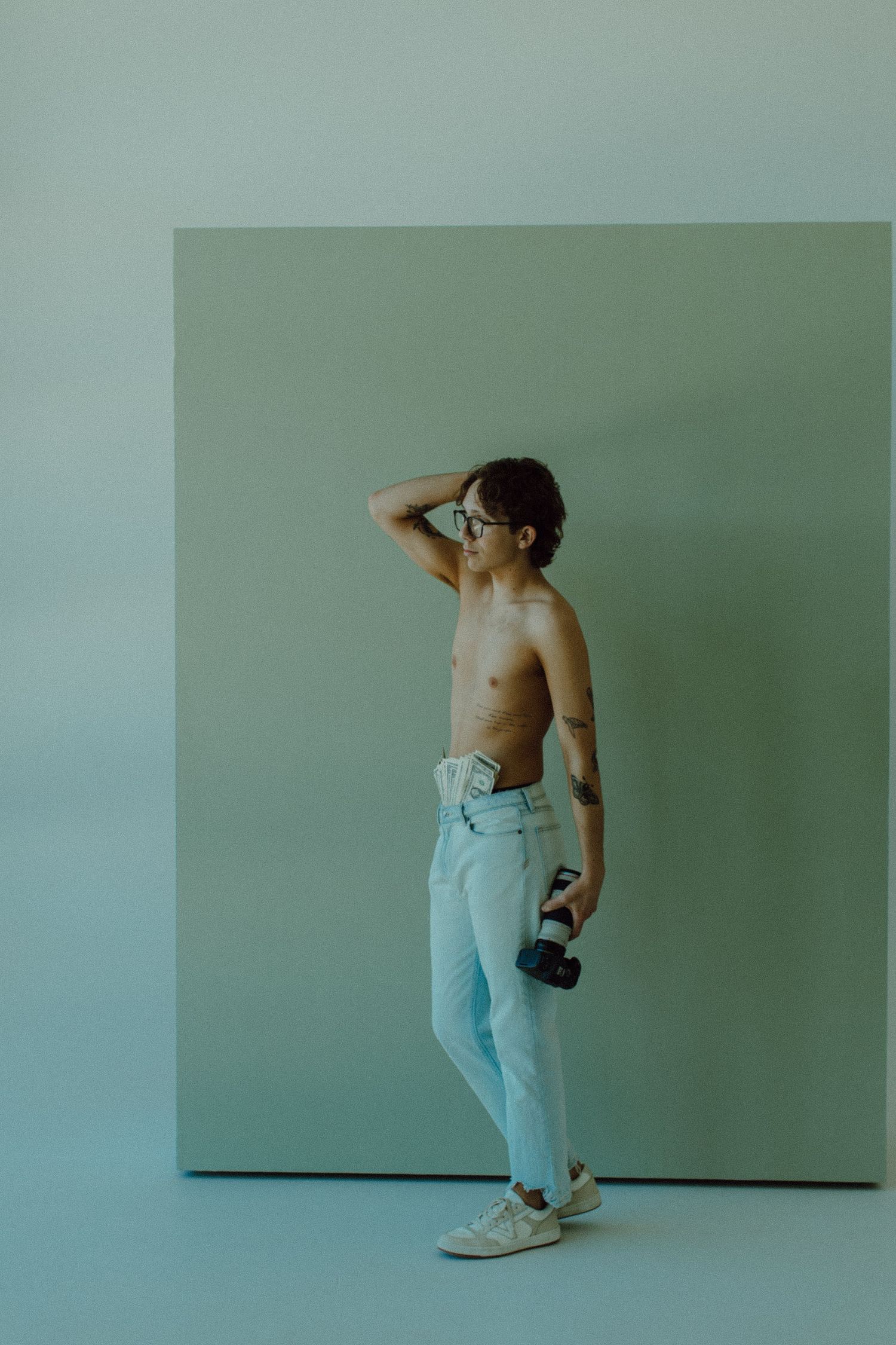 Gavin shirtless holding his camera facing to the left
