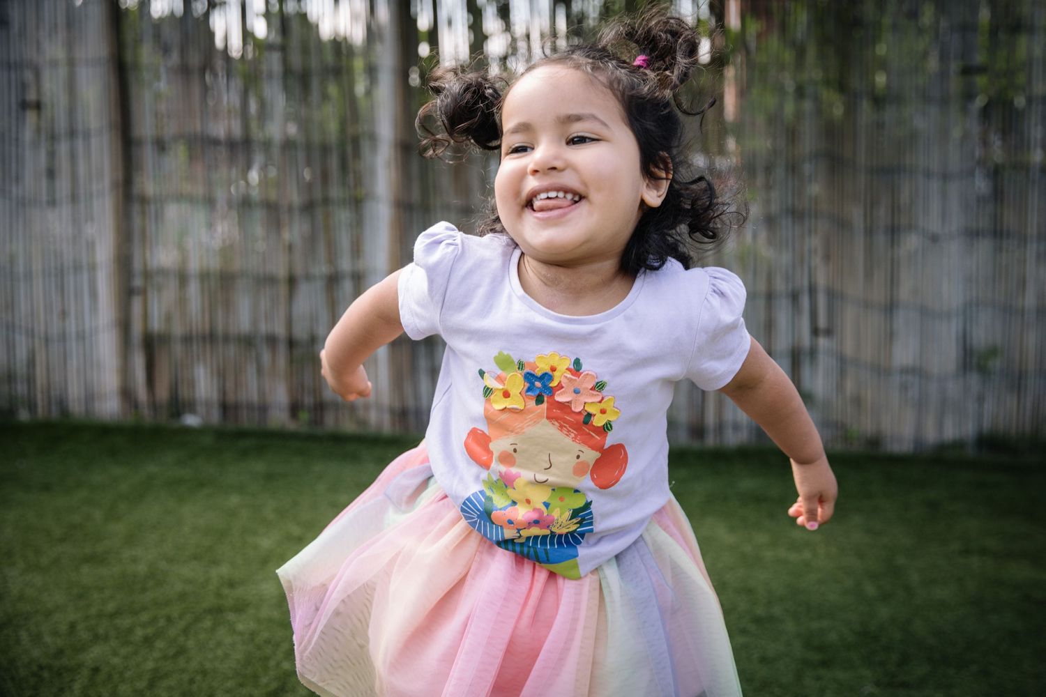 A joyful moment in a backyard wearing a tutu and decorative t-shirt while dancing and laughing.