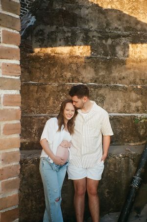 A couple sharing an intimate moment against a rustic brick wall background.