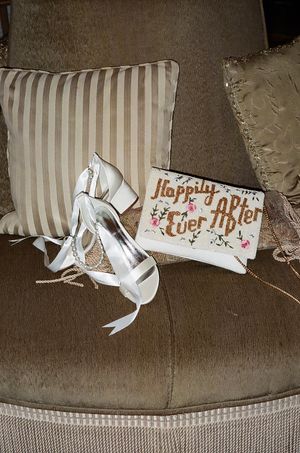 White bridal shoes and a wedding card arranged on a striped cushion.