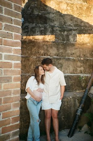 A couple sharing an intimate moment against a rustic brick wall.