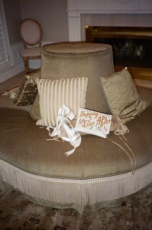 Wedding accessories and pillows arranged on a round velvet ottoman.