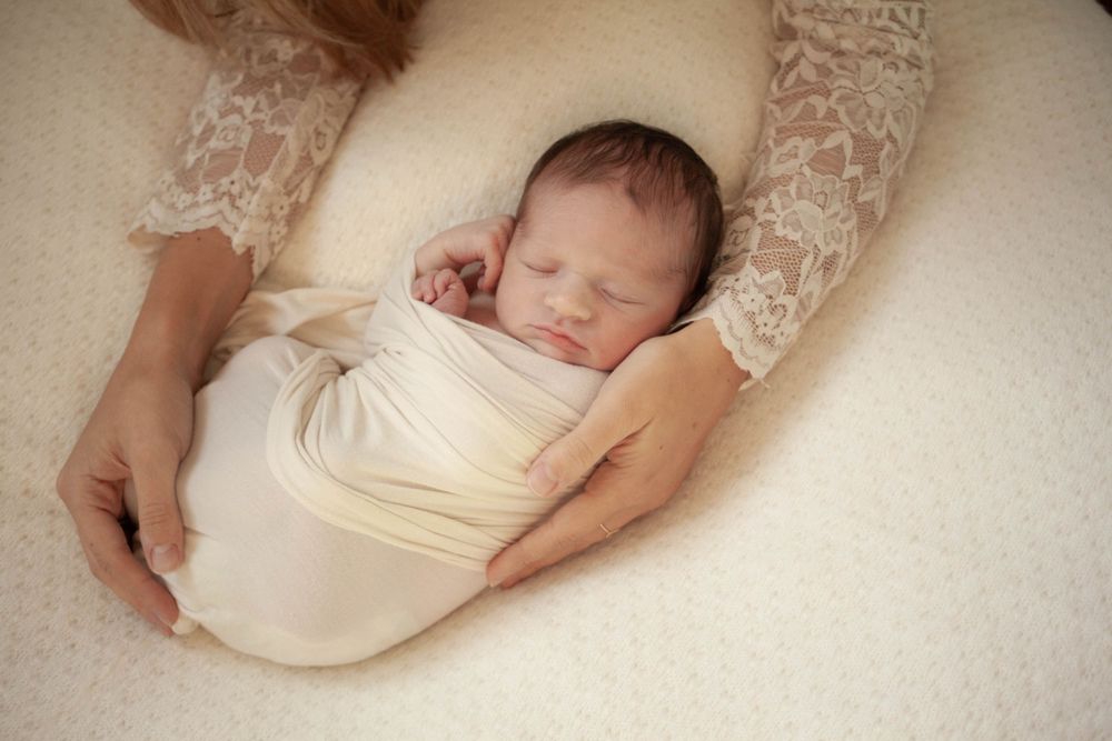 neonato con wrap di cotone, dorme posato sul bean bag con copertina lana, sessione luce naturale a domicilio a Peschiera Borromeo e Milano