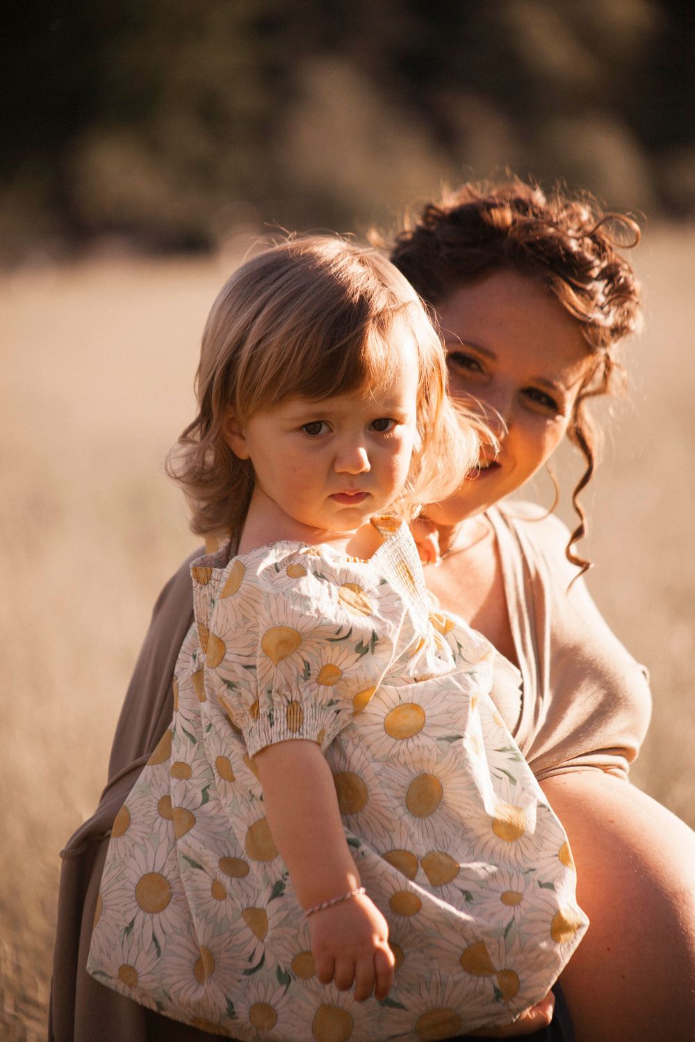 bimba con mamma incinta, sorella, pancione, sessione fotografica esterna, campo fiori spighe, abbraccio mamma figlia, fotografia di famiglia