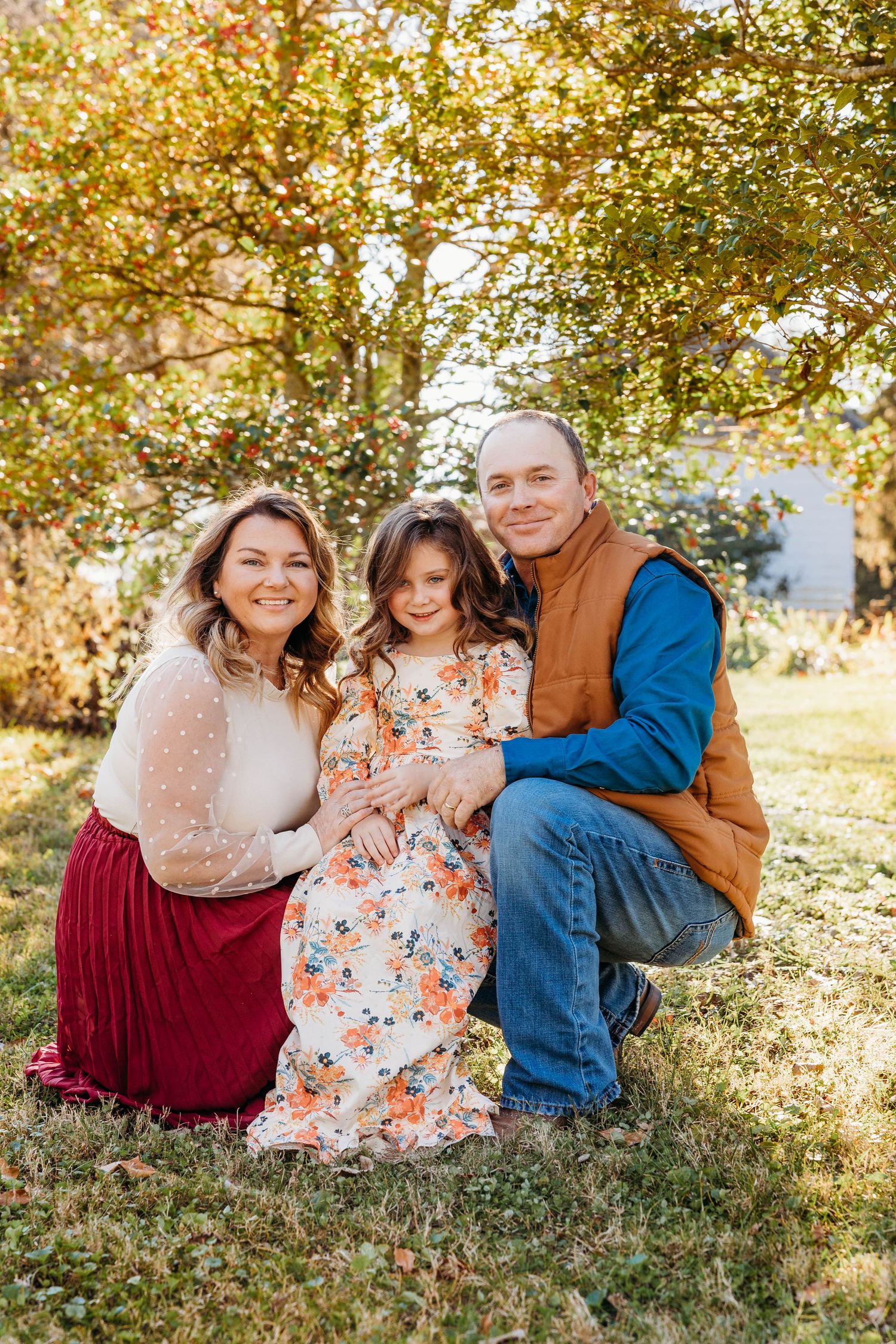 Family sitting together outdoors during autumn photo session.