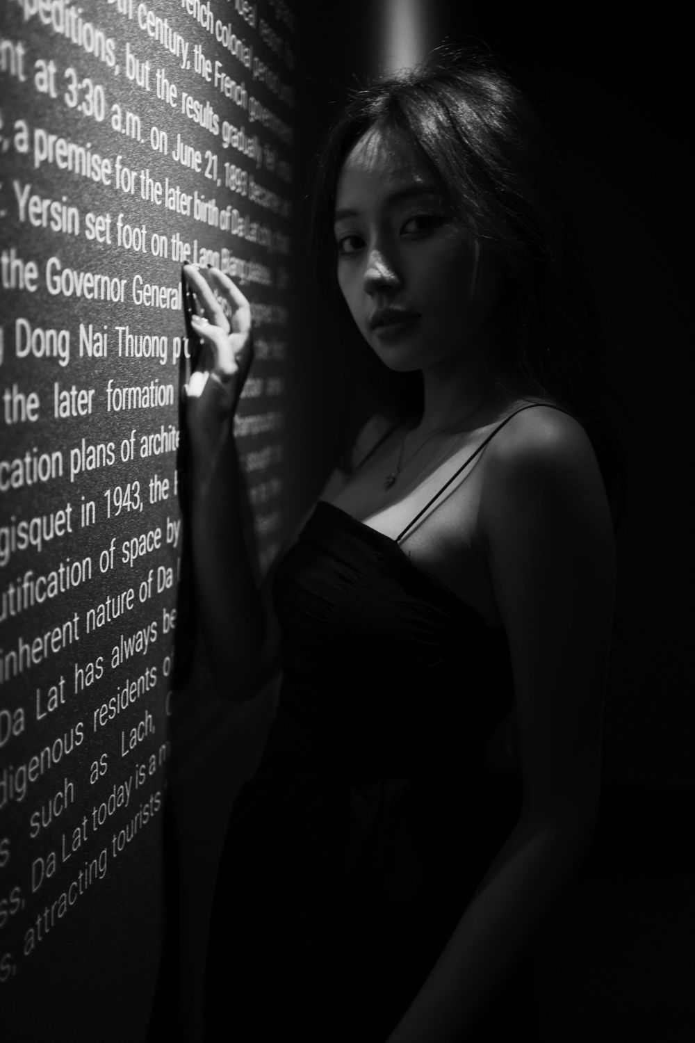 Dramatic silhouette against illuminated text wall in moody black and white composition.