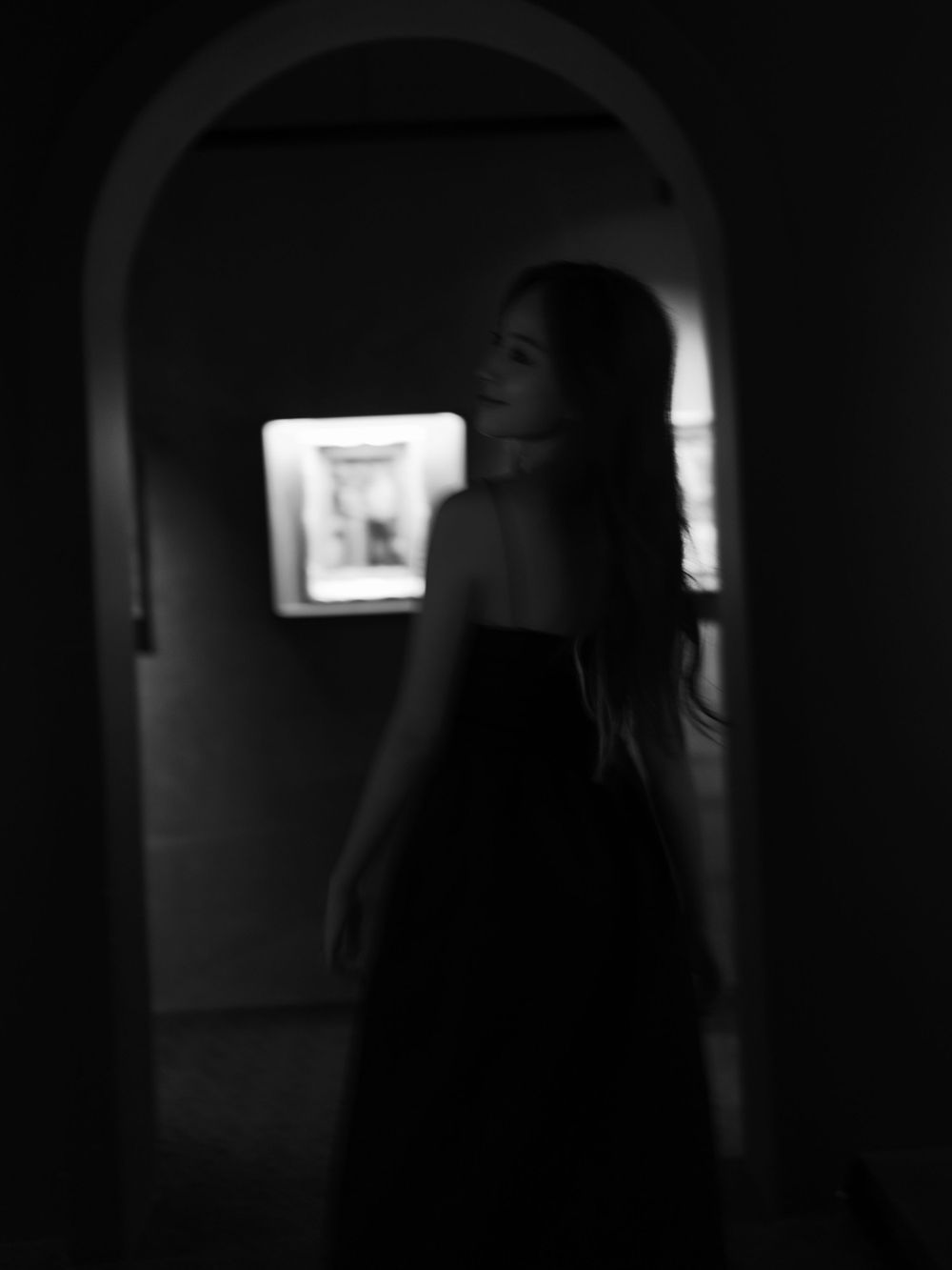 Moody silhouette through archway with dramatic lighting and gallery setting.