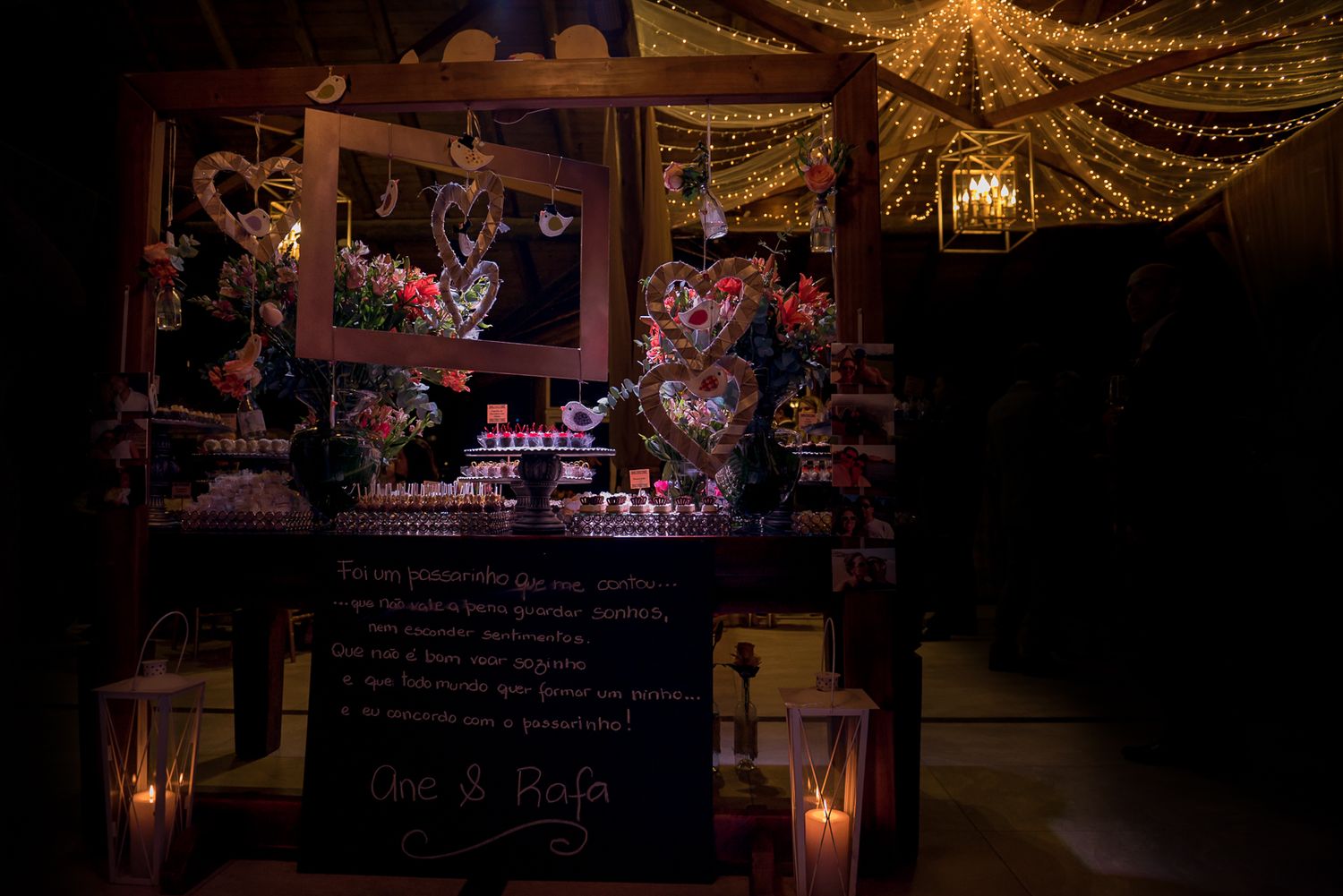 Romantic dessert display with string lights and candles creating an intimate wedding atmosphere.