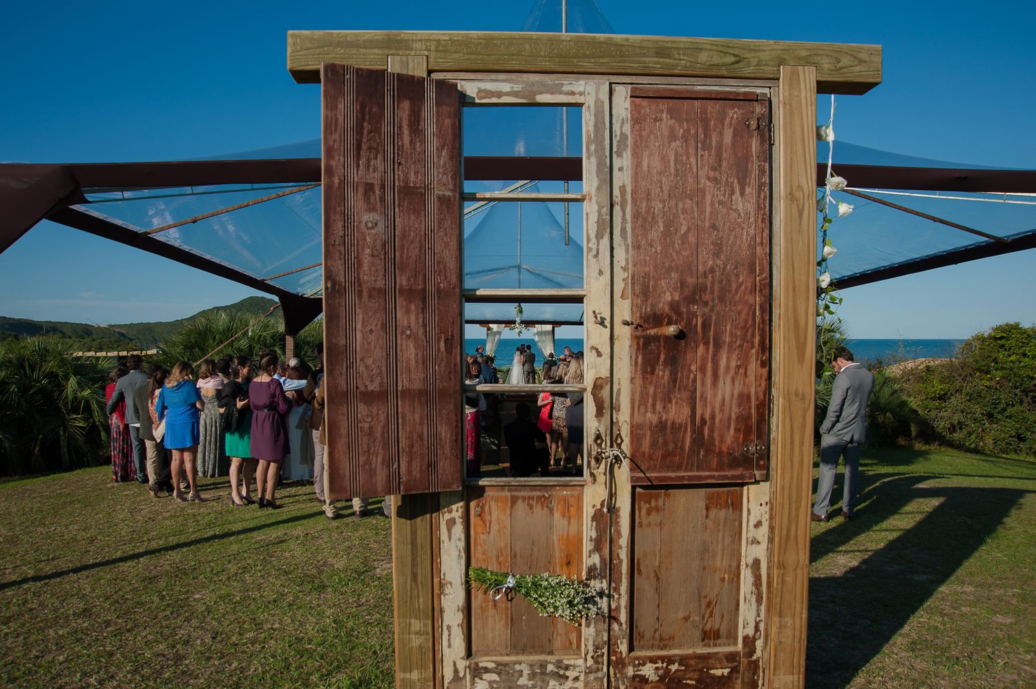 Rustic wooden door frame decorated for a wedding ceremony with ocean view.