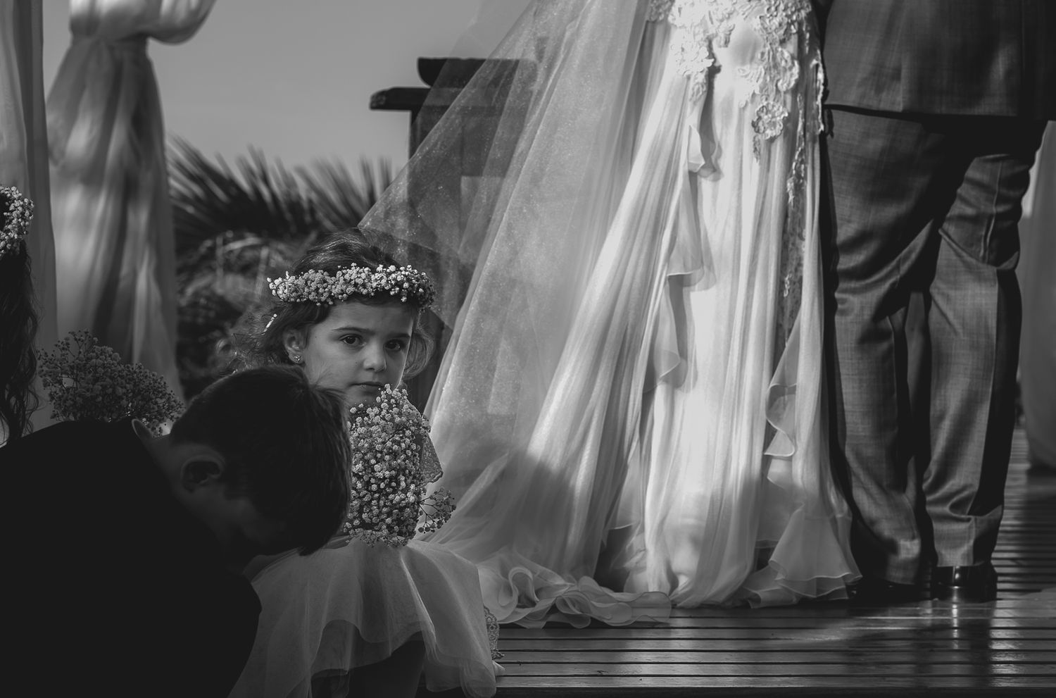 Black and white photo of wedding ceremony details with flowing fabric and decorative elements.