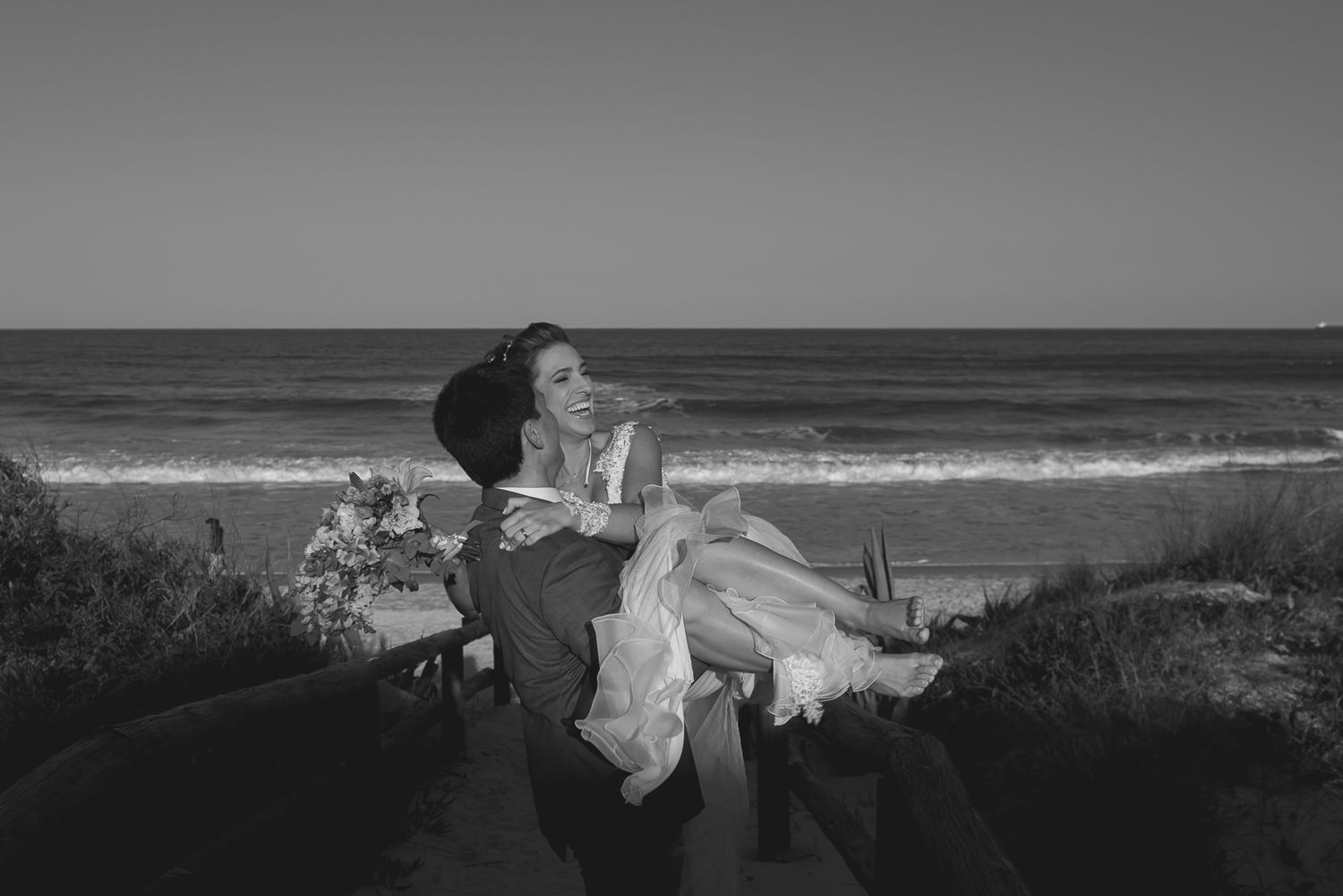 A romantic seaside moment with the couple embracing against an ocean backdrop.