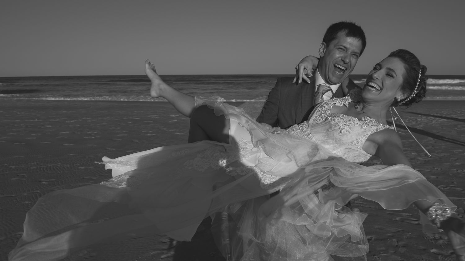 A playful moment captured on the beach with the couple in formal wedding attire.