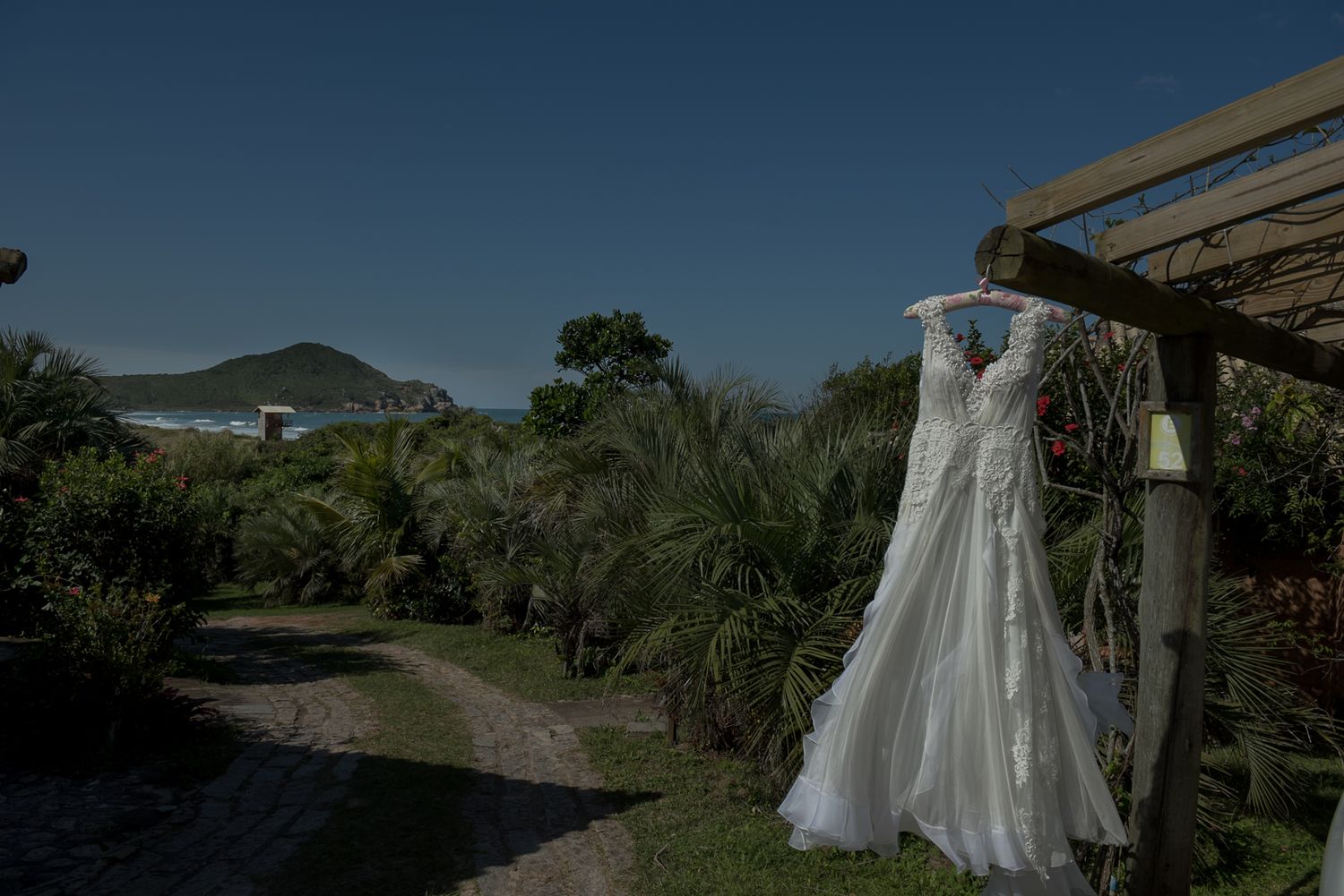 A white wedding dress hanging outdoors against a mountain landscape backdrop.