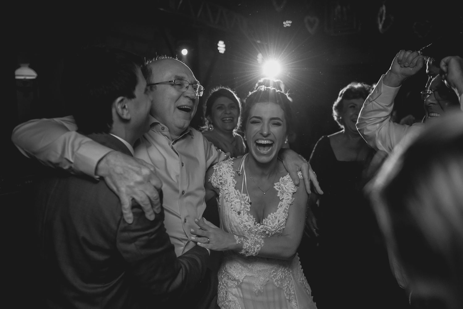 Black and white candid photo of guests laughing and celebrating at a wedding reception.