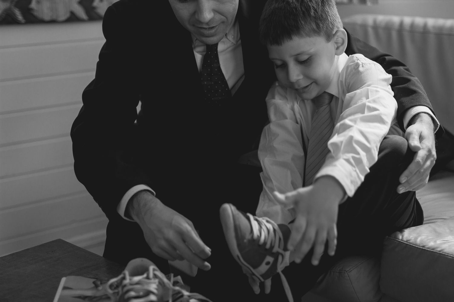 A black and white candid moment showing shoe preparation for a special event.