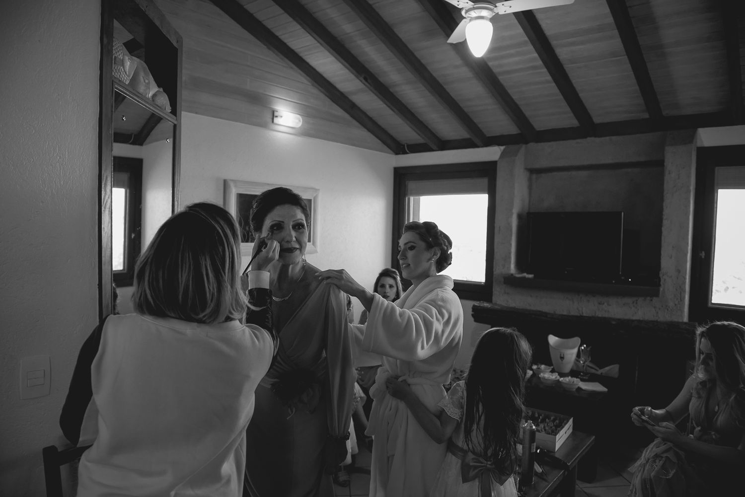 A black and white image showing preparation activities in a room with wooden beams.