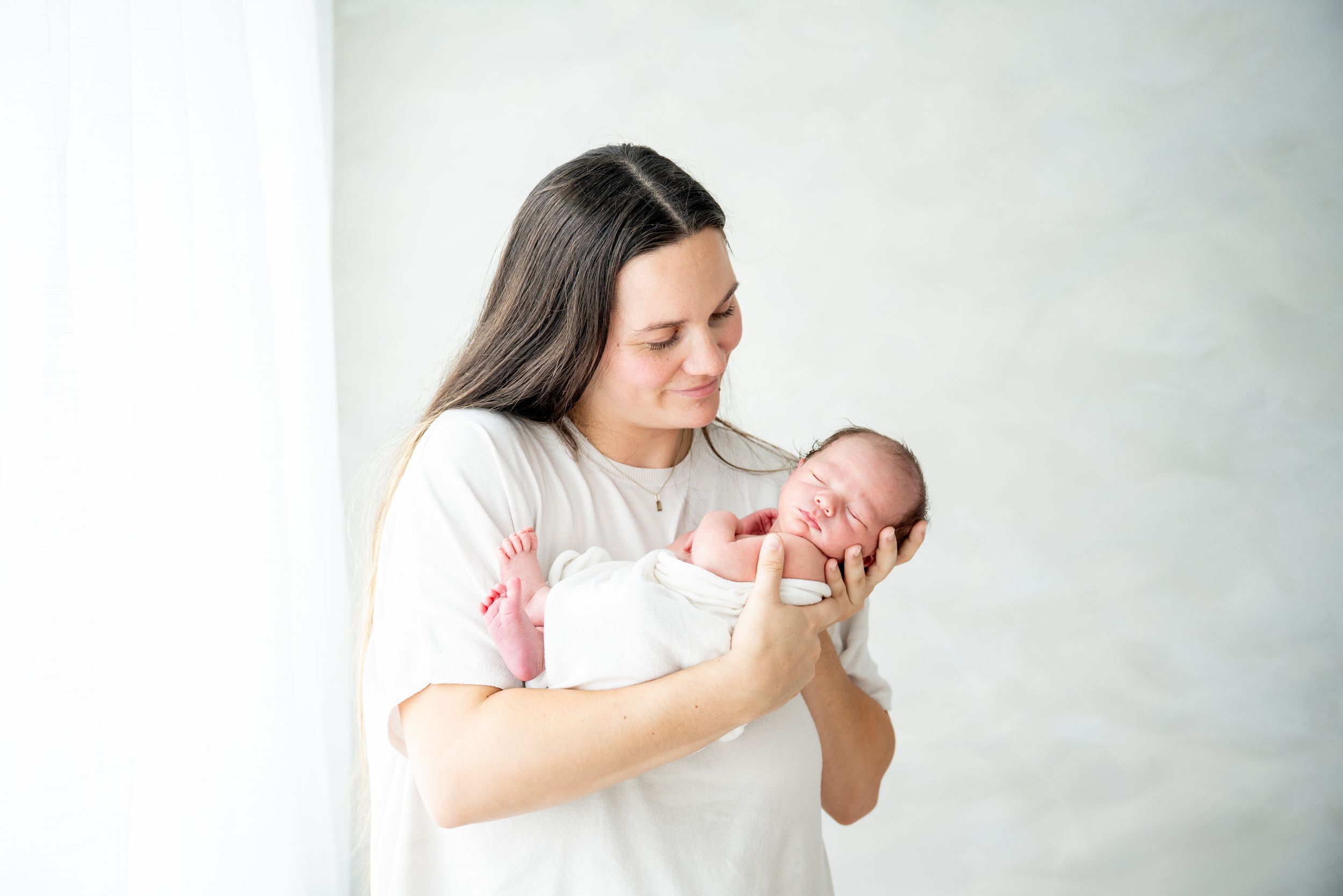 Minimalist newborn photography session against white background.