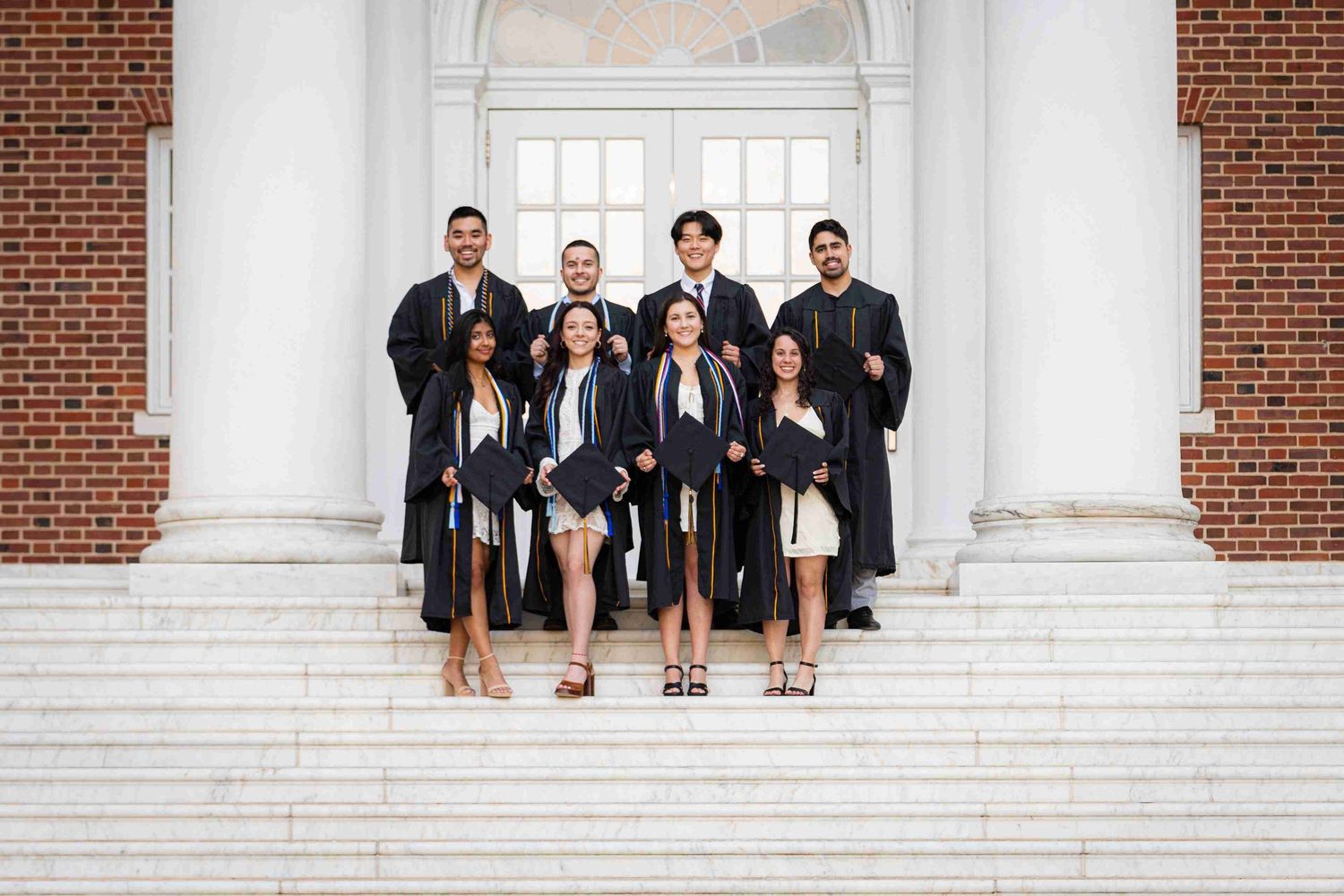 Formal group photo of graduates in black robes on university steps.