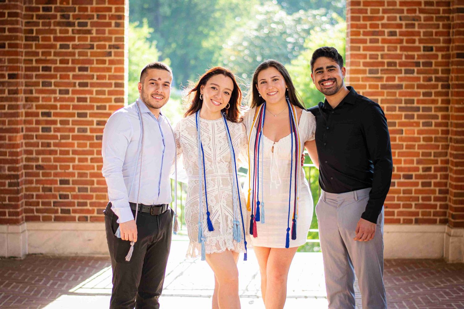 Group portrait of graduates in casual attire against brick university backdrop.