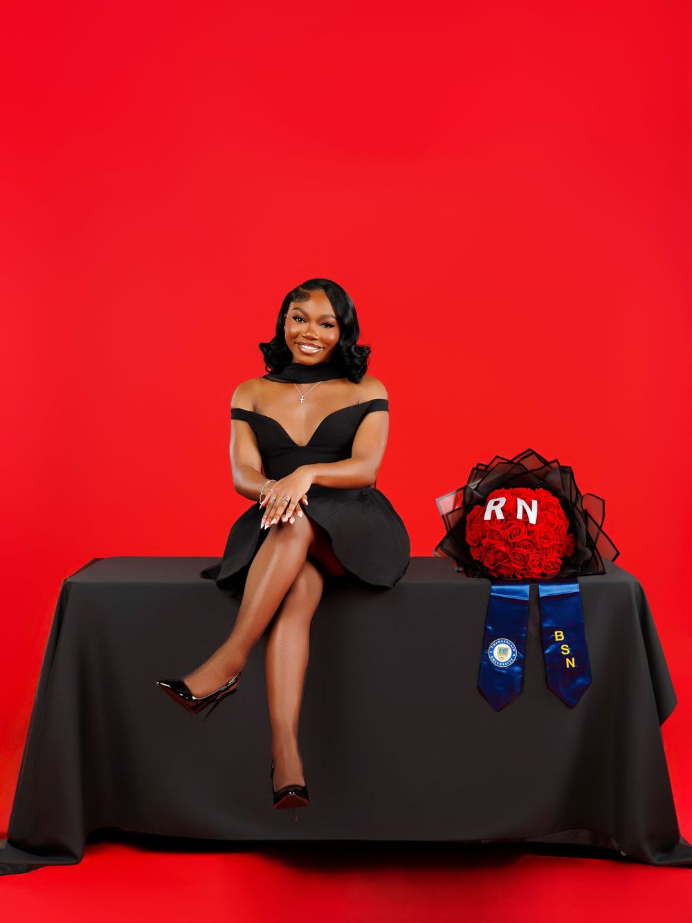 A person in a black dress poses on a dark couch against a bright red background in a stylized photo series.