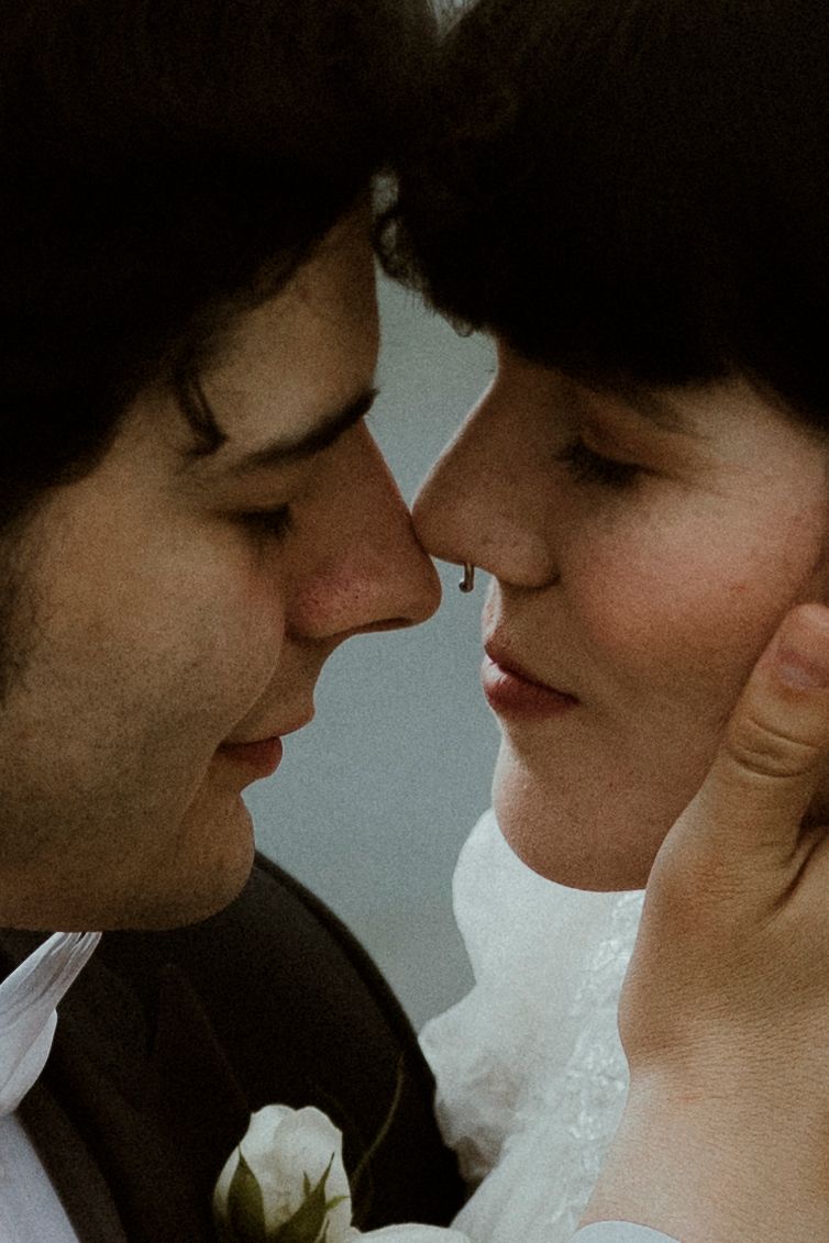 An intimate black and white portrait of newlyweds sharing a close moment.