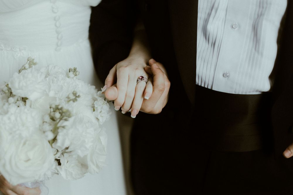Close-up details of a white wedding dress and floral bouquet in dramatic lighting.