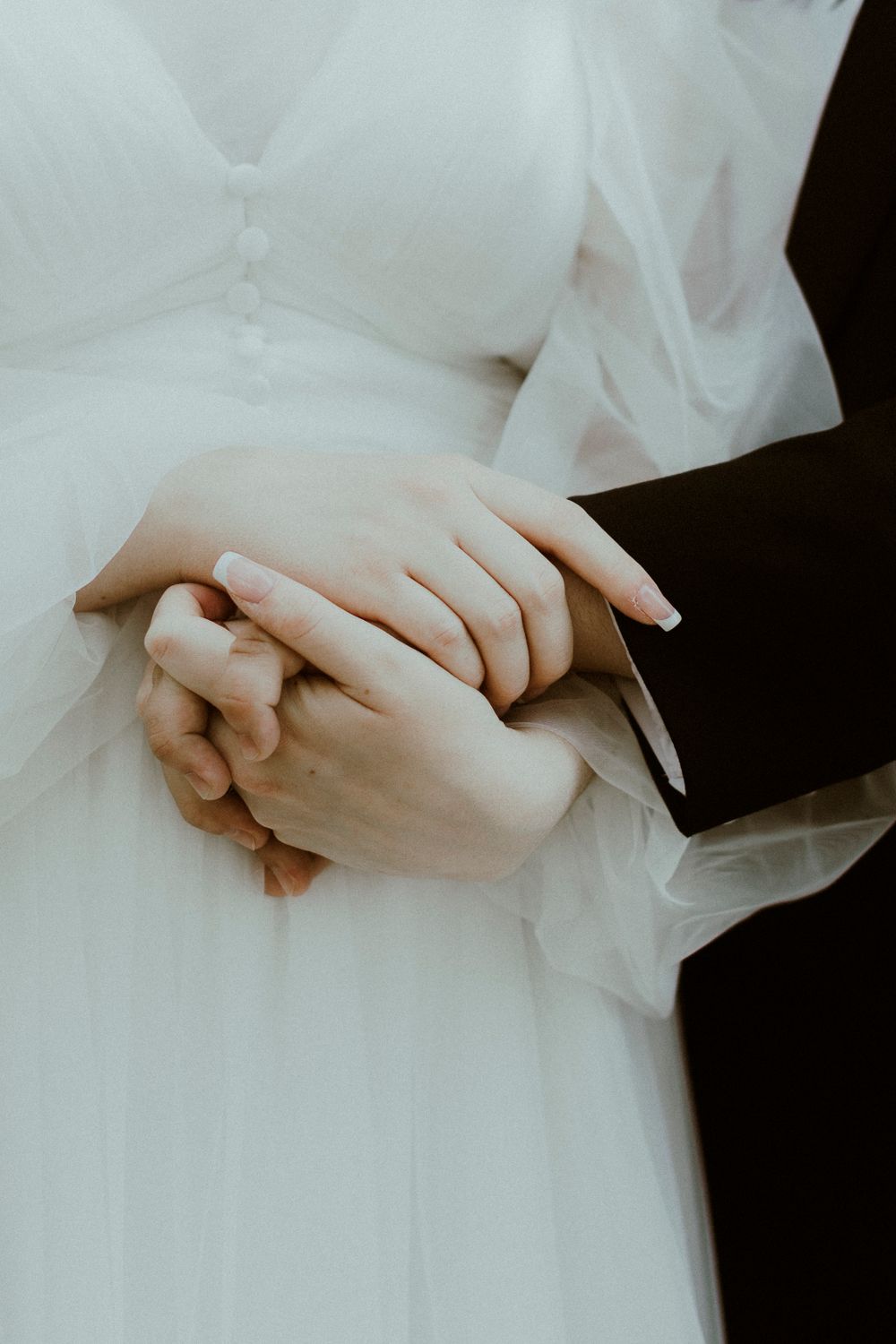 Elegant hands draped in white tulle fabric against a dark background.