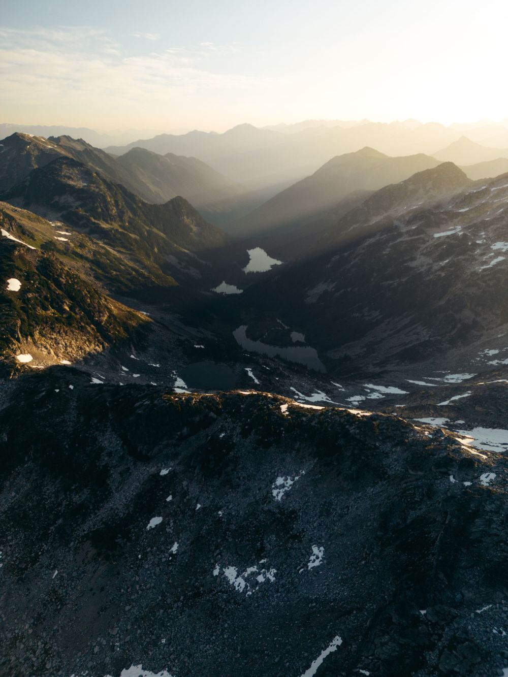 Aerial view of mountainous valley with winding lakes during golden sunset light.
