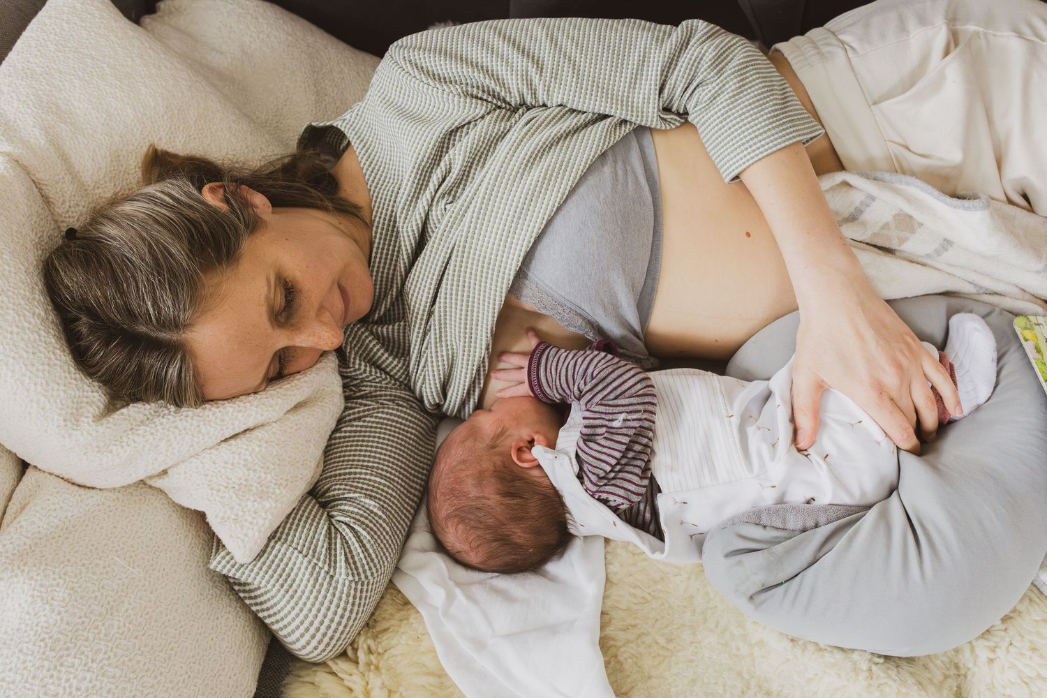Schwarz-Weiß-Foto eines neugeborenen Babys das auf den Beinen der Mutter liegt und gähnt, entstanden bei einer Wochenbettreportage.