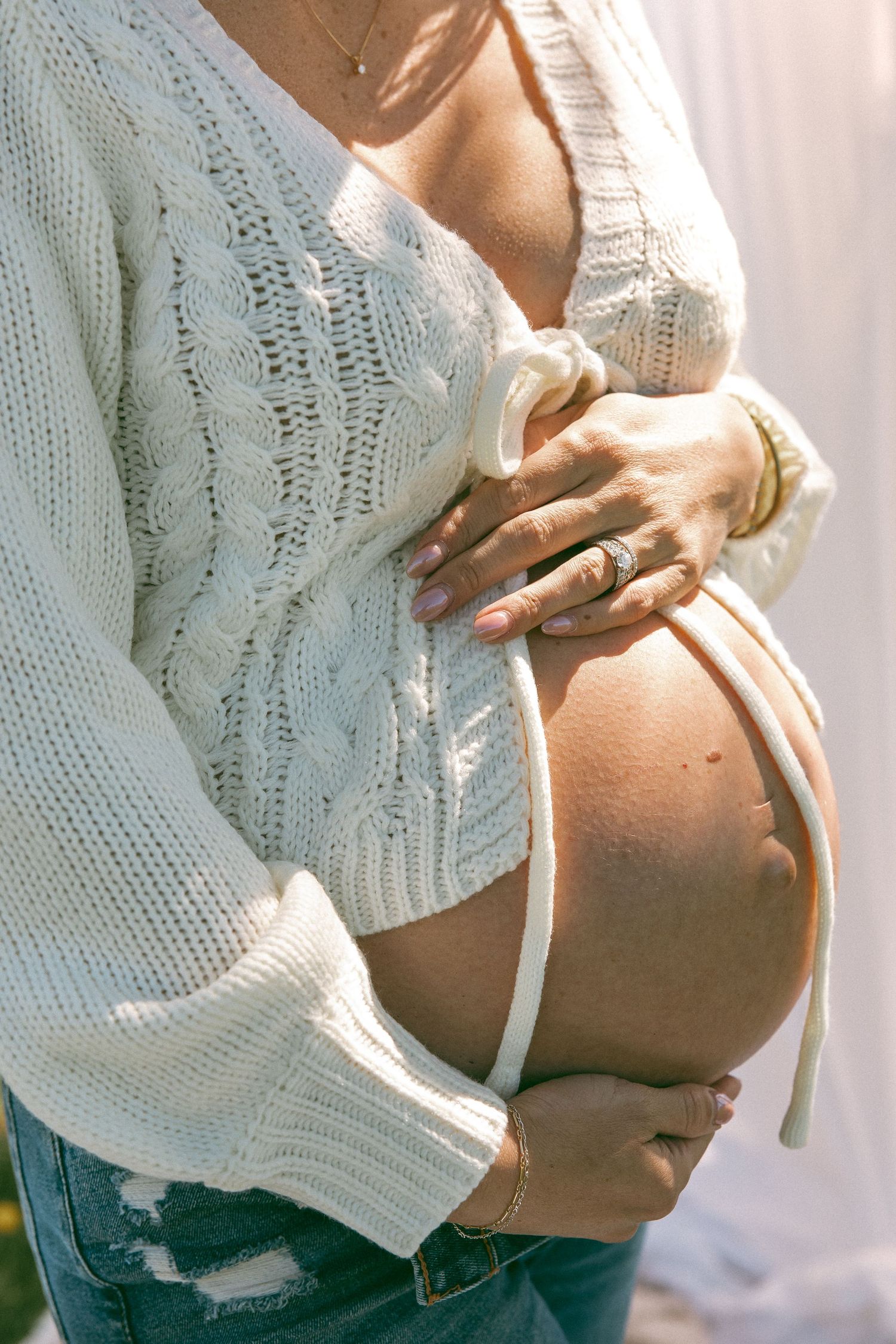 Someone wearing a cozy white sweater and blue jeans rests comfortably on a light colored surface.