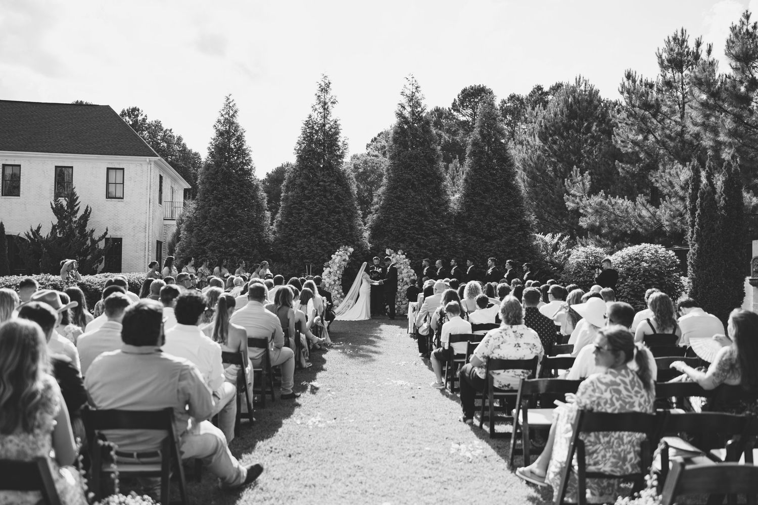 Outdoor wedding ceremony with rows of white chairs on a sunny day. Separk Mansion Wedding Photographer