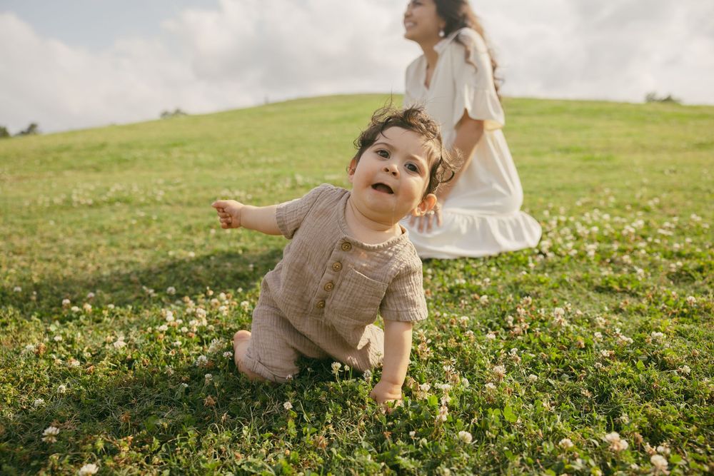 Small child plays in a blooming meadow while wearing light colored clothing on a sunny afternoon.
