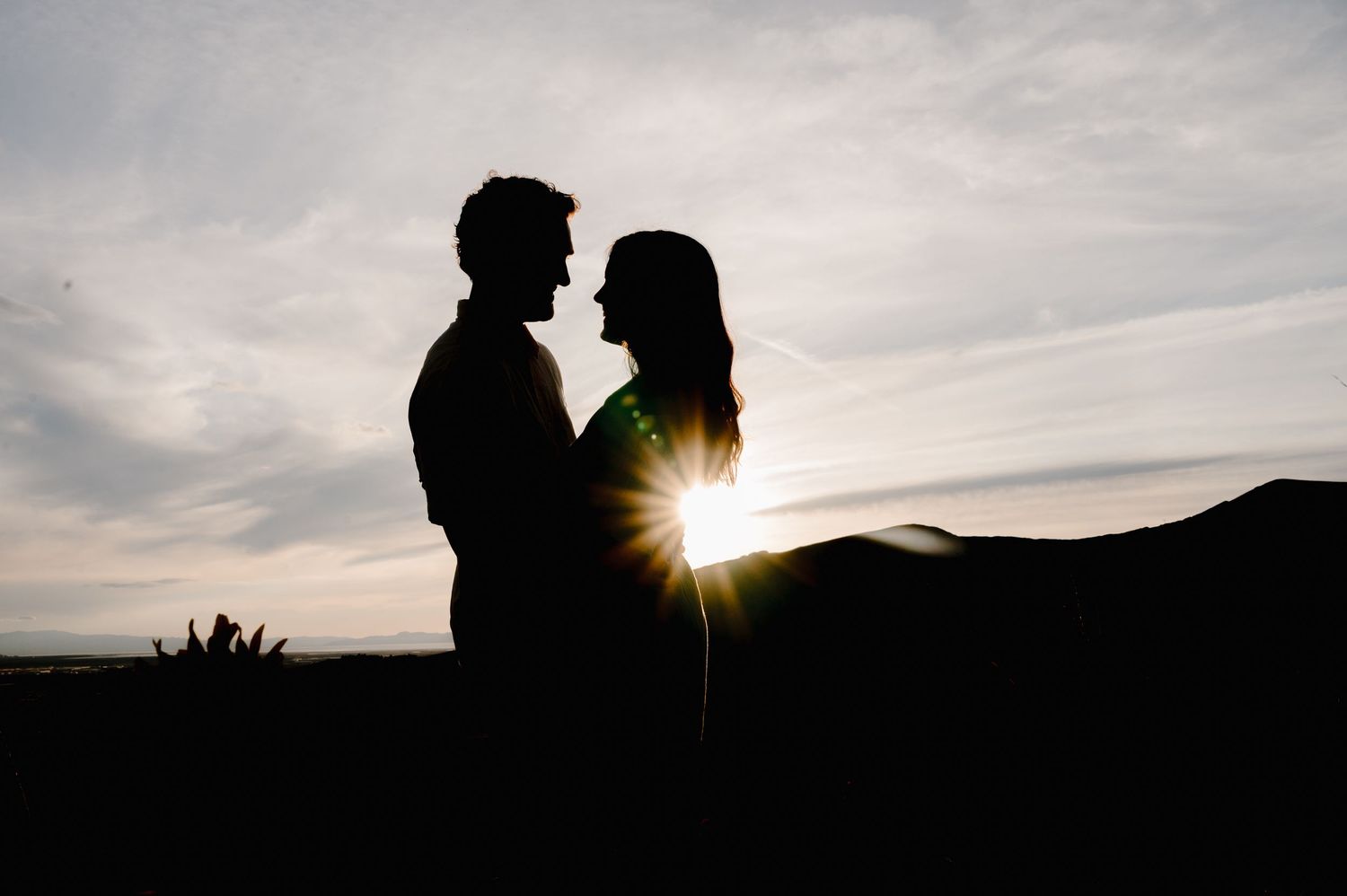 A romantic silhouette of a couple against a sunset mountain backdrop.