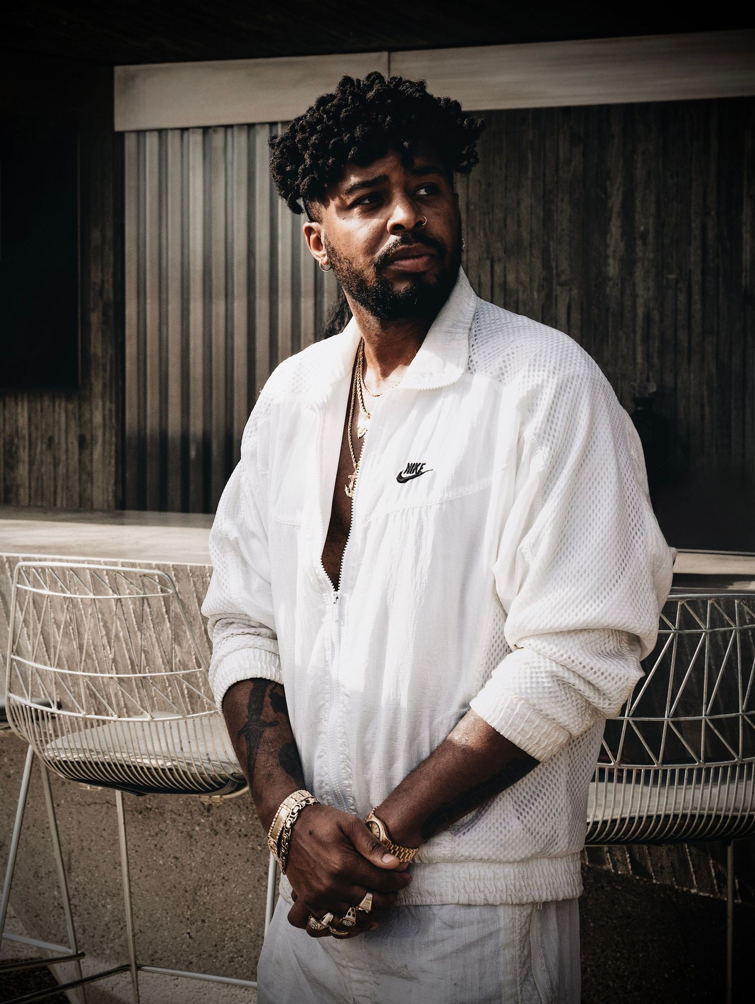 A figure in a white Nike shirt sits on outdoor patio furniture in a moody black and white photograph.