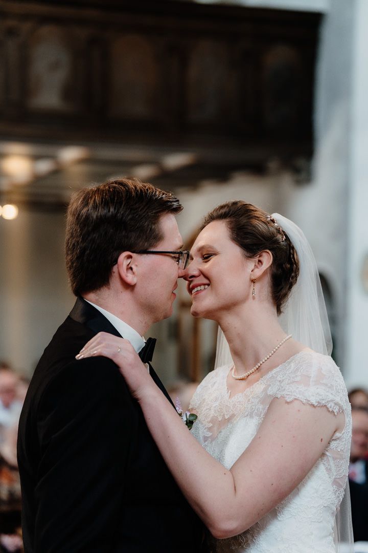 The bride and groom share an intimate moment during their wedding ceremony in a church setting.