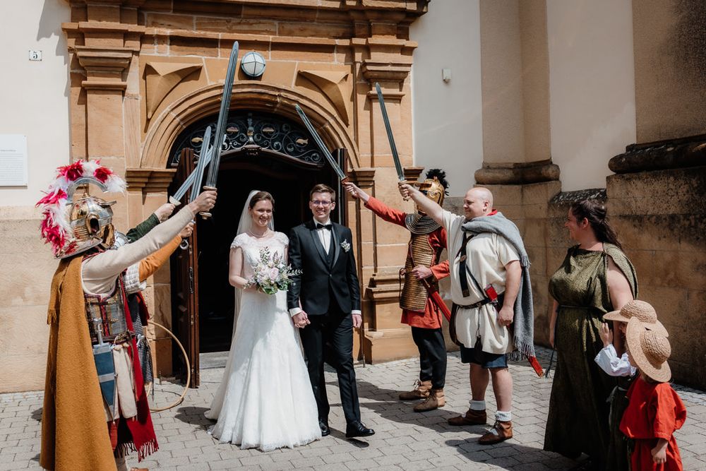 Costumed performers create a ceremonial sword arch at a church wedding exit.