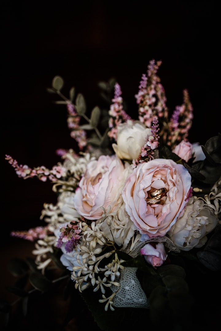 Elegant floral arrangement with pink roses and delicate purple flowers in a silver vase.