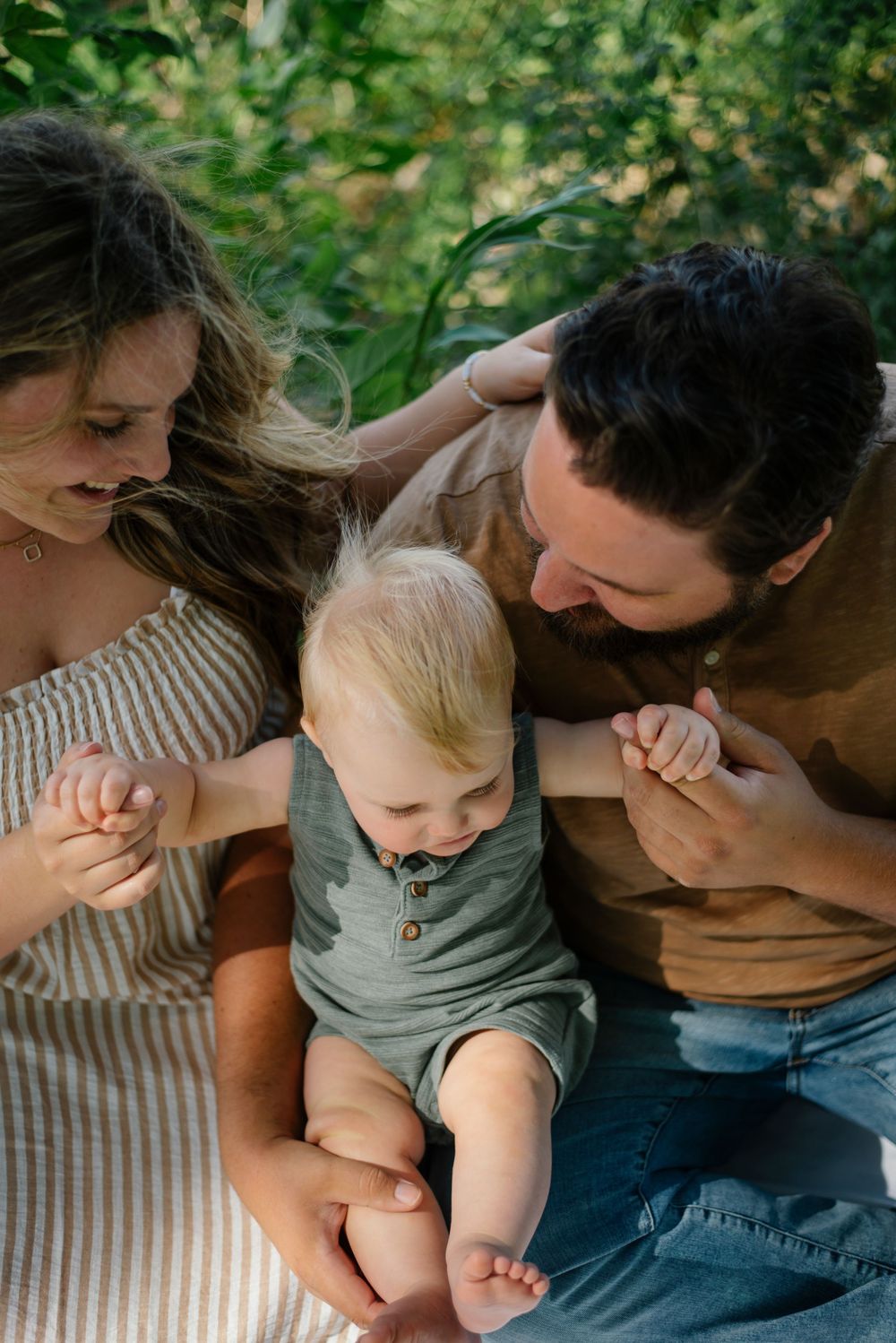 An intimate family moment captured on a striped blanket outdoors.