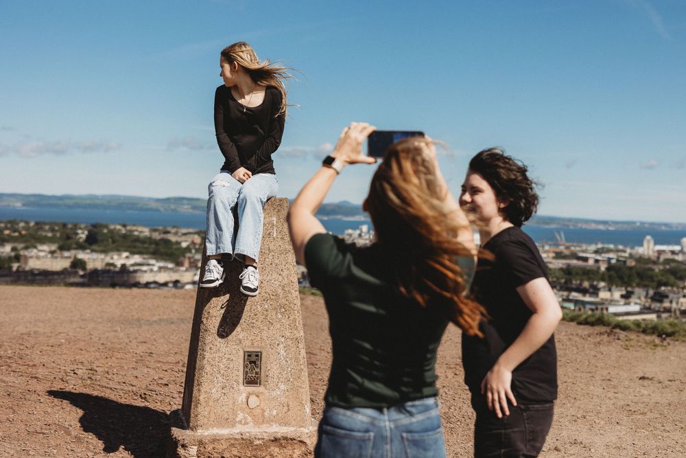 Groups of friends having fun taking photos at a scenic hilltop viewpoint.