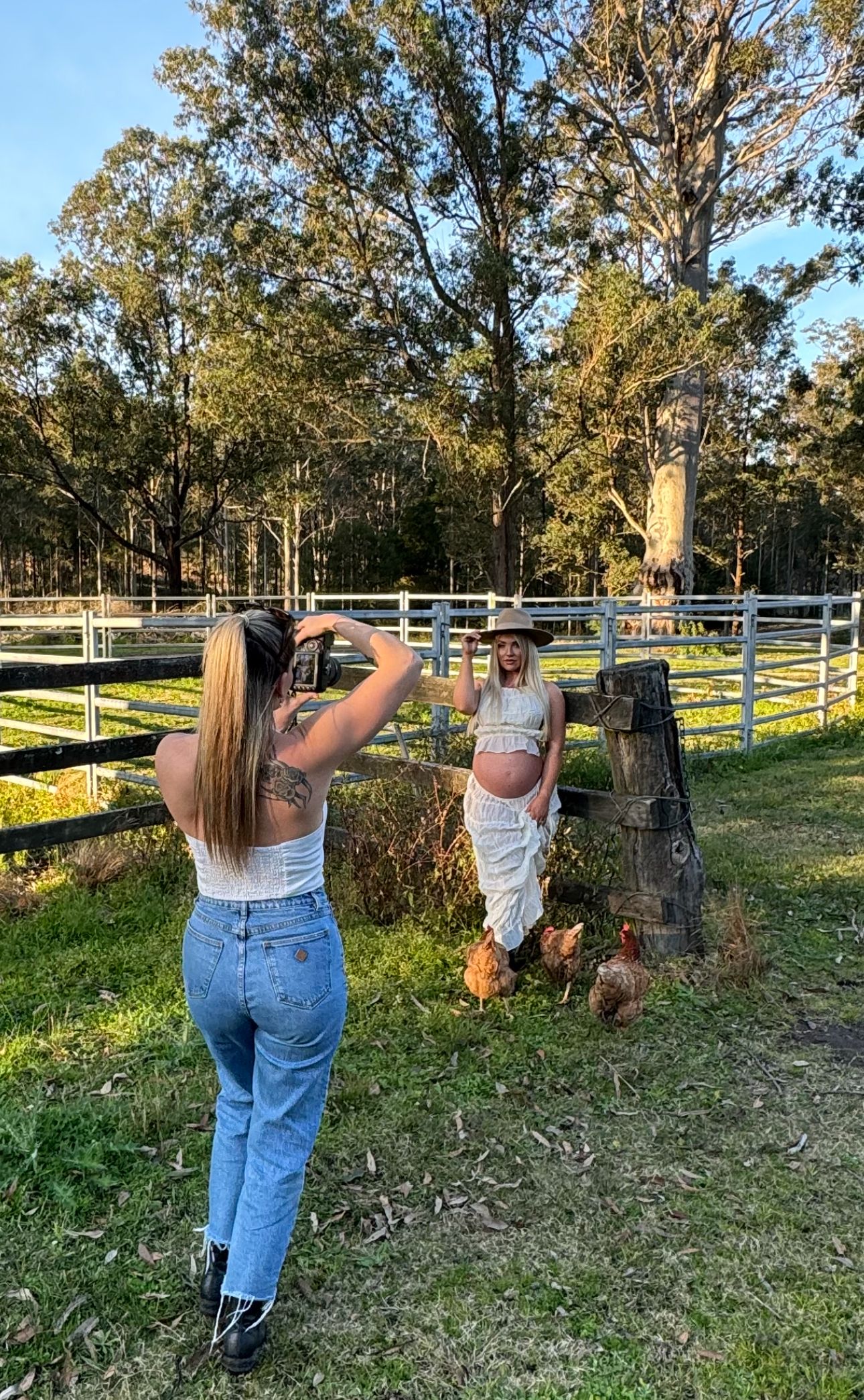 Behind the scenes photo of maternity photoshoot with photographer and chickens on farm.