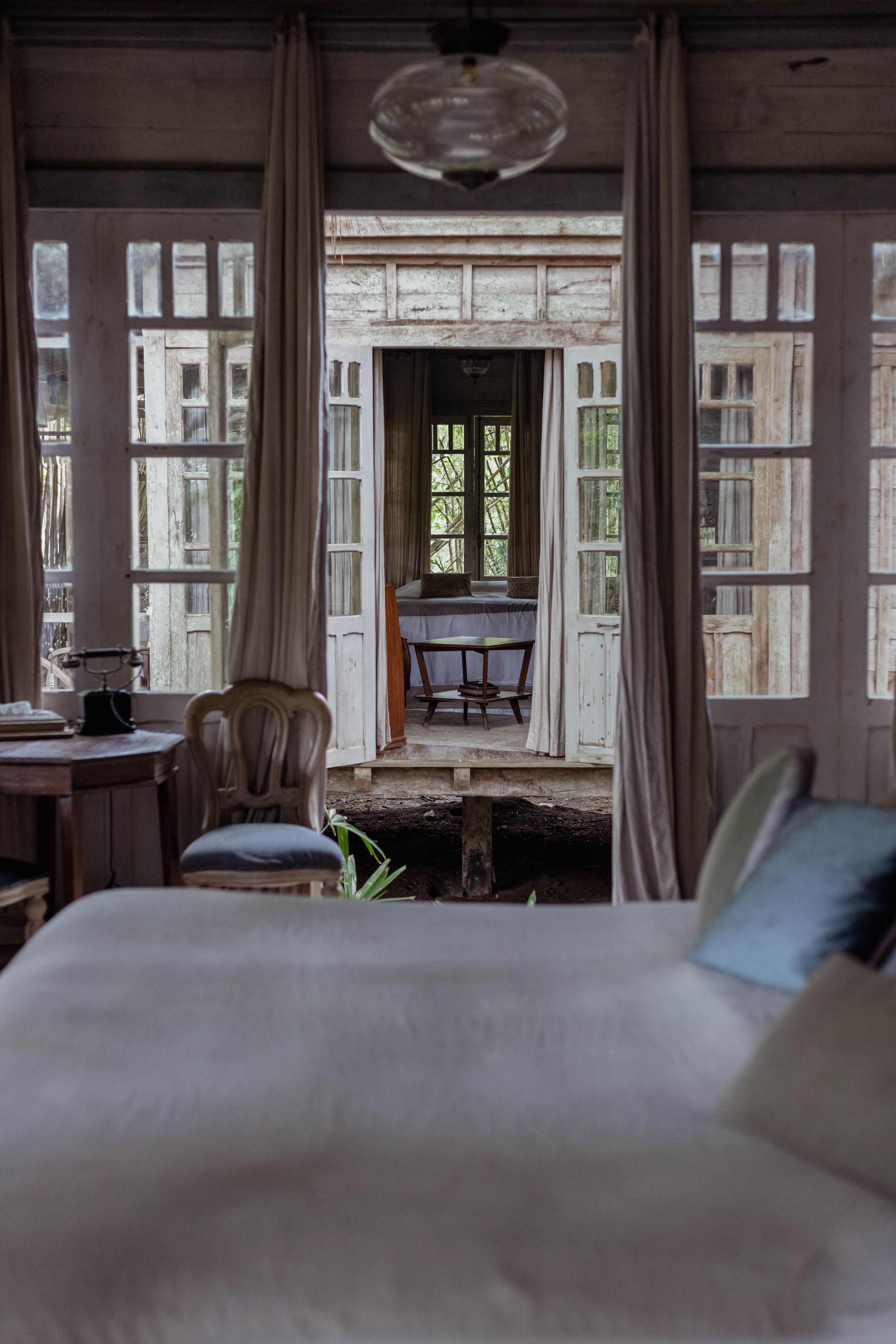 Elegant bedroom interior with French doors, vintage furniture and natural lighting.
