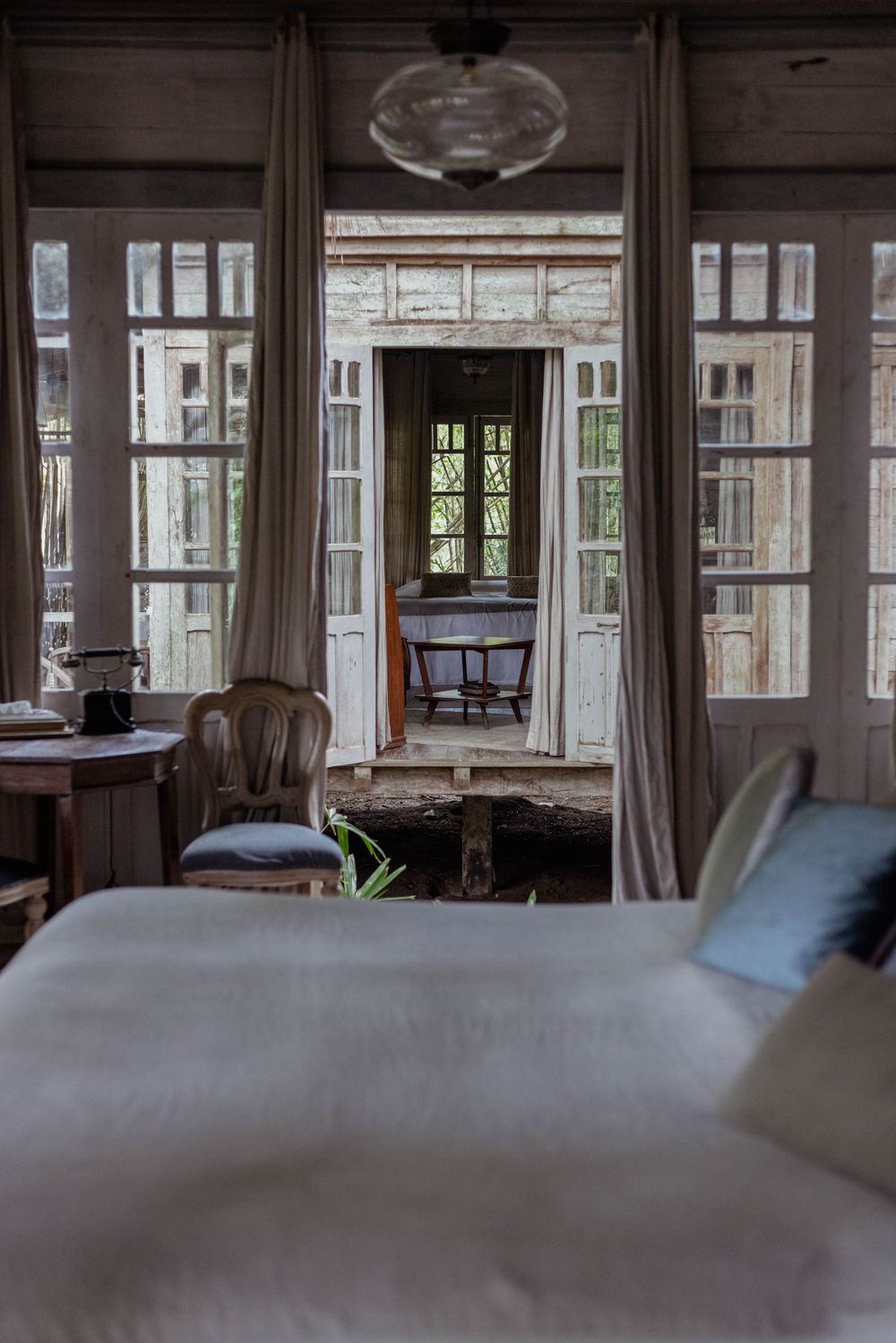 Elegant bedroom interior with French doors, vintage furniture and natural lighting.