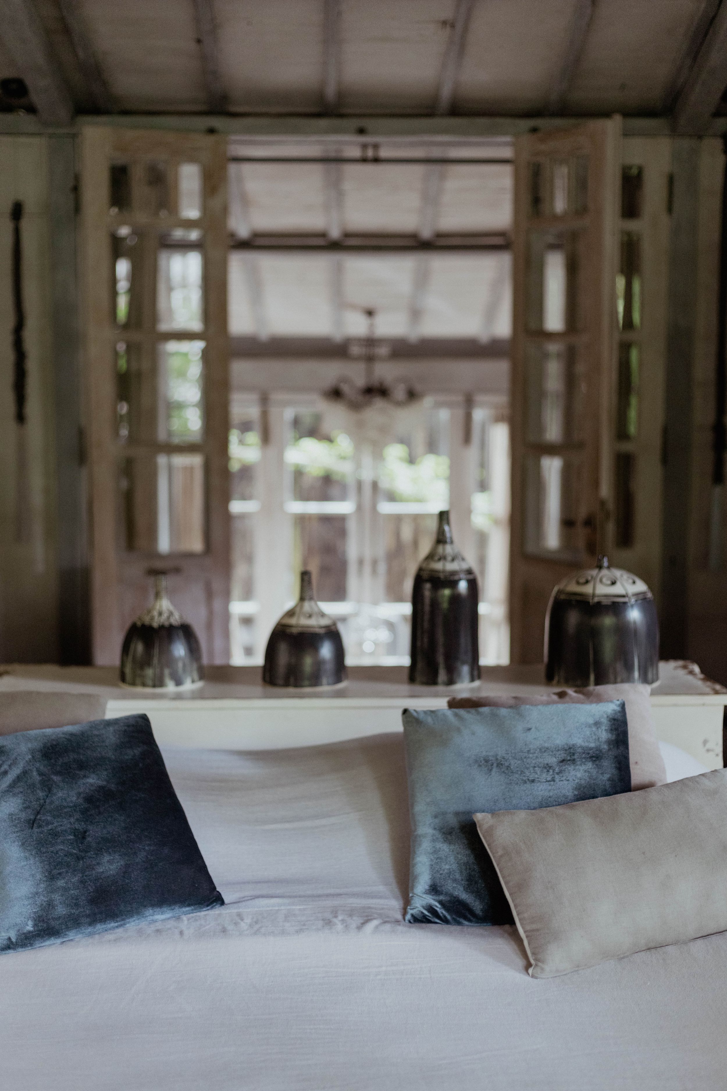 Cozy bedroom interior with soft cushions and vintage bell jar lights on display.