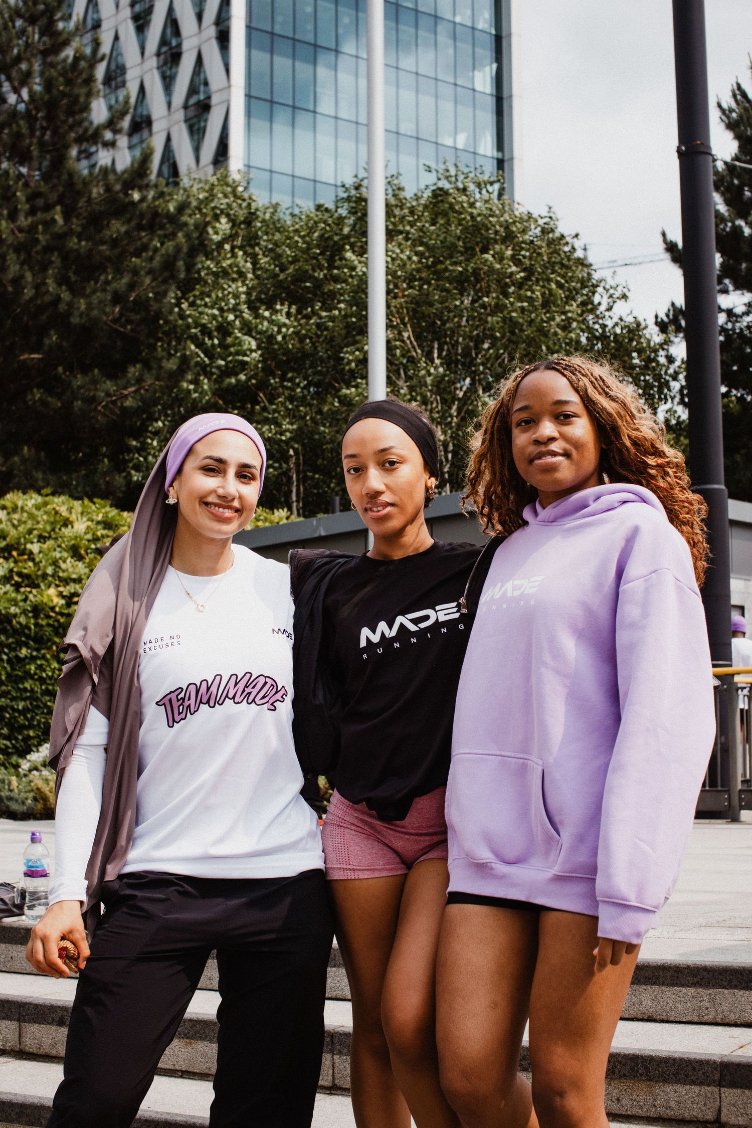 A group of runners in coordinated pink, white and black sporty casual outfits posing together outdoors.