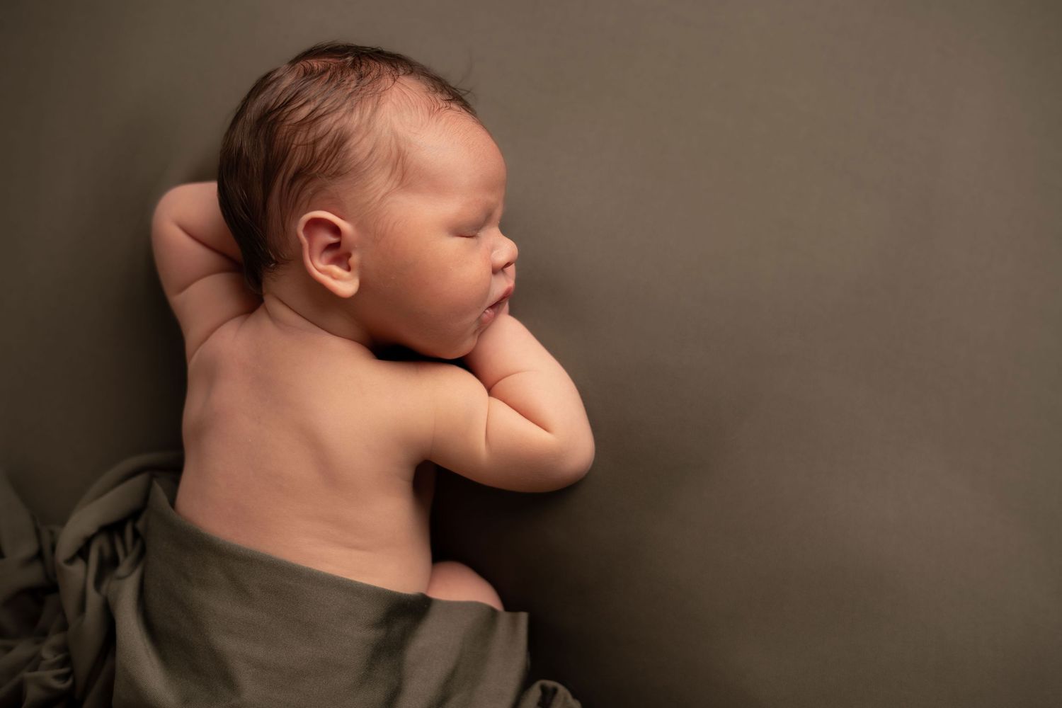 Nyfødtfotografering i studio - sovende gutt med grønn bakgrunn