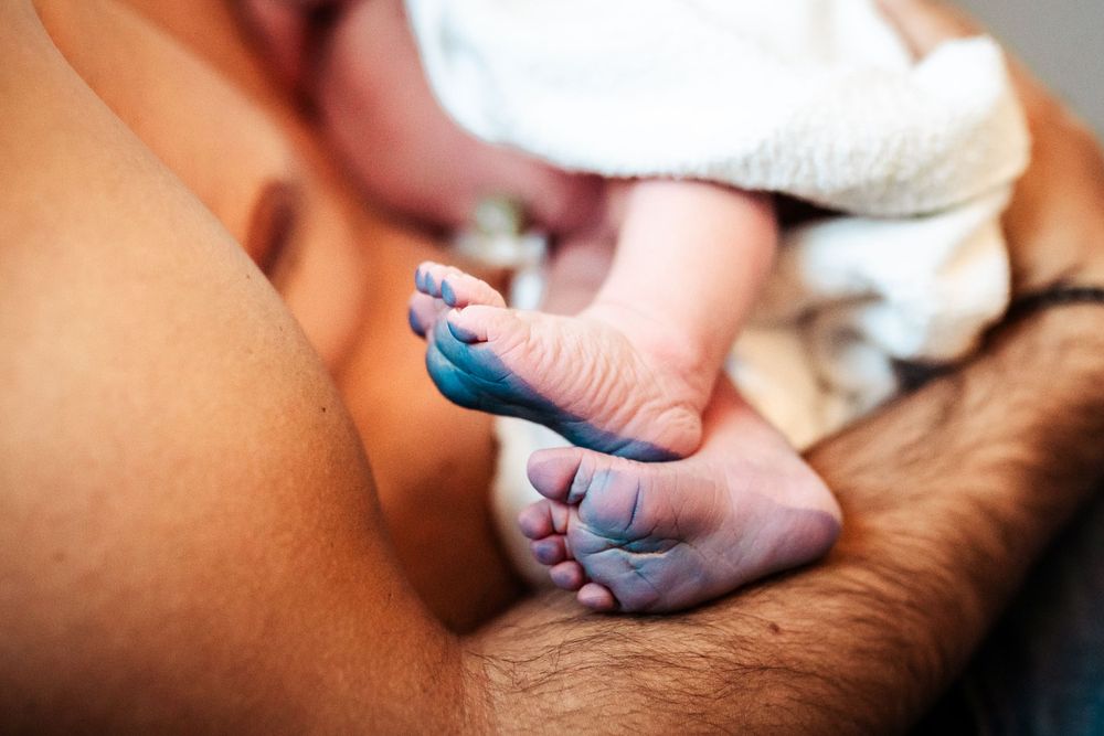 Close-up of tiny newborn feet with medical identification bands in hospital.