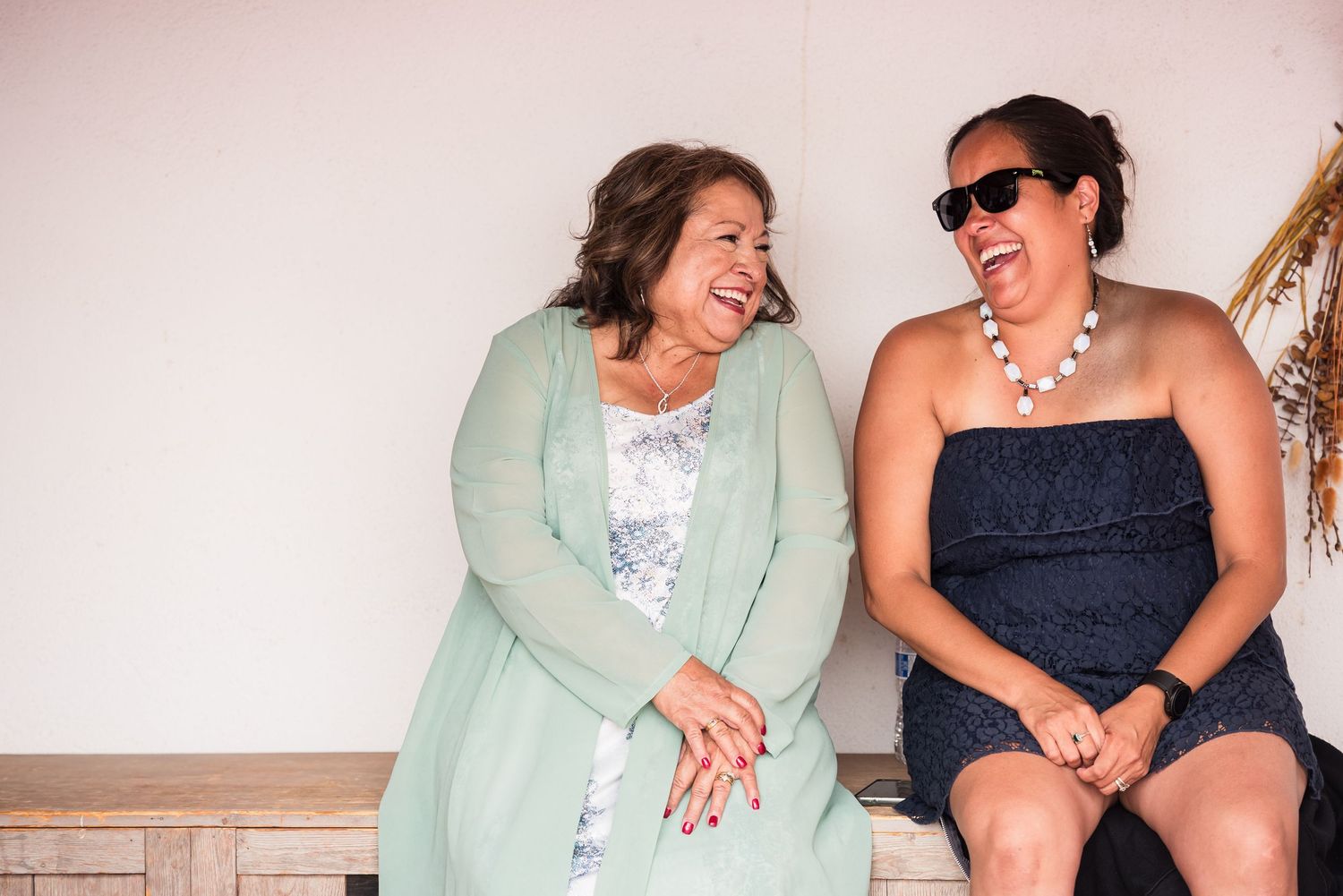 Two guests share a candid moment of laughter while sitting together.