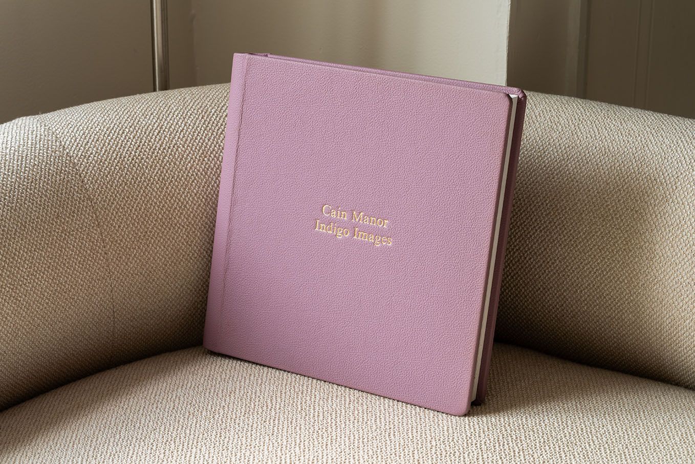 Black leather wedding album book resting on wooden surface.