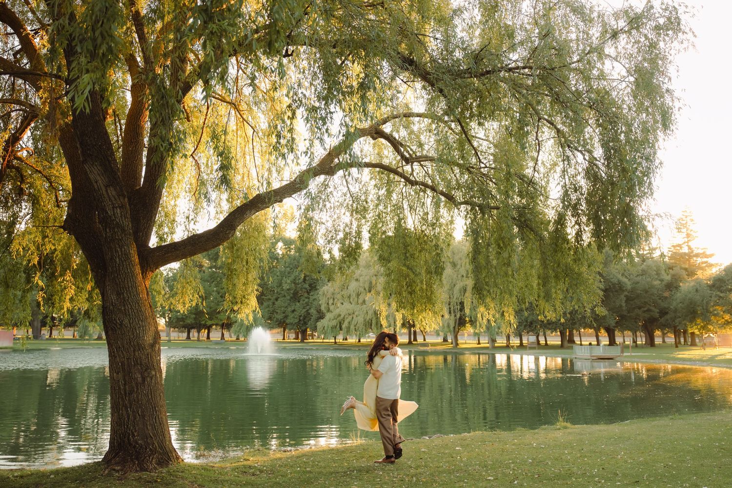 A couple poses for their anniversary shoot in Elk Grove, CA in front of a lake. Photographed by Shumesa Mohsin